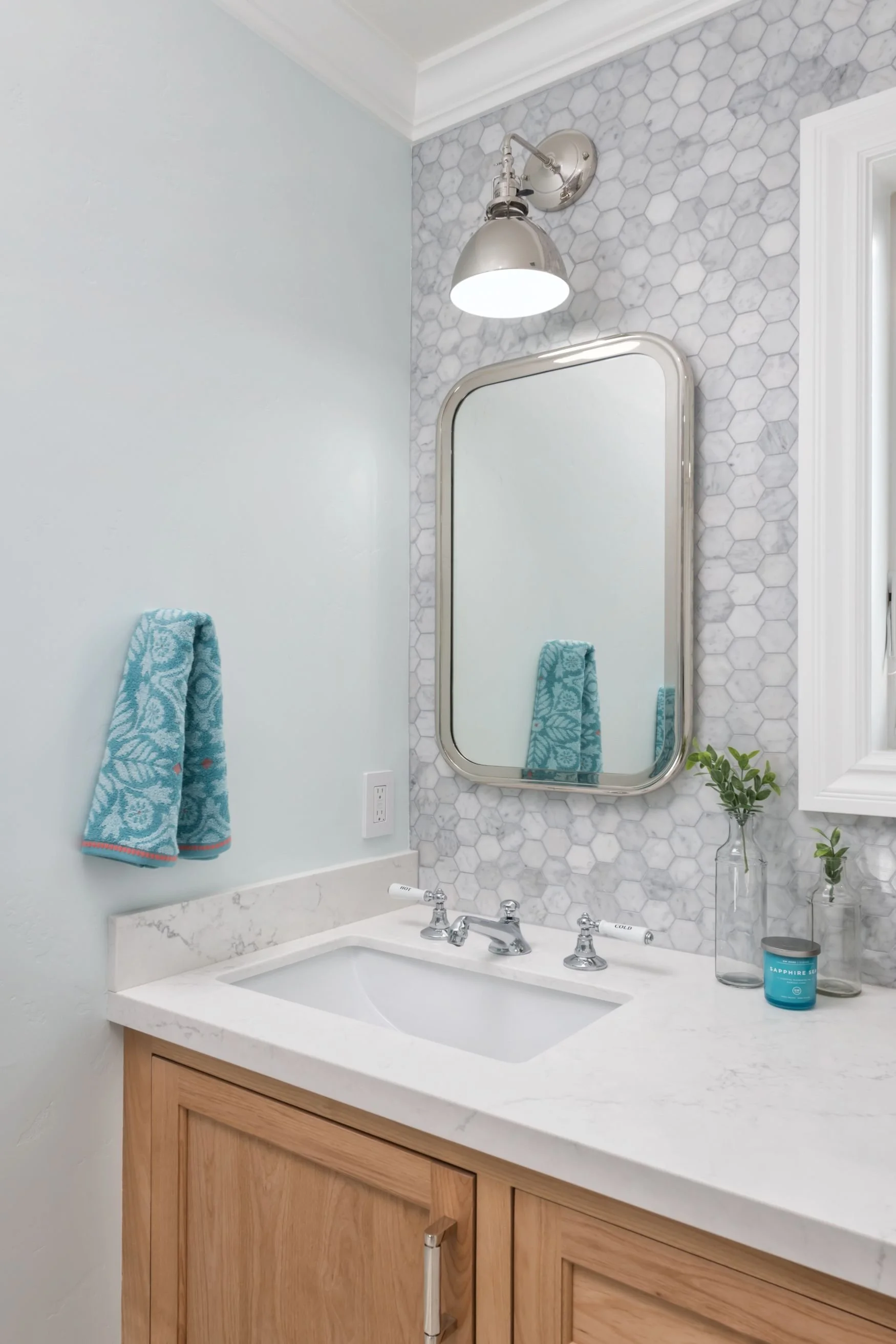 Carrara marble backsplash with polished nickel mirror and sconce with oak vanity
