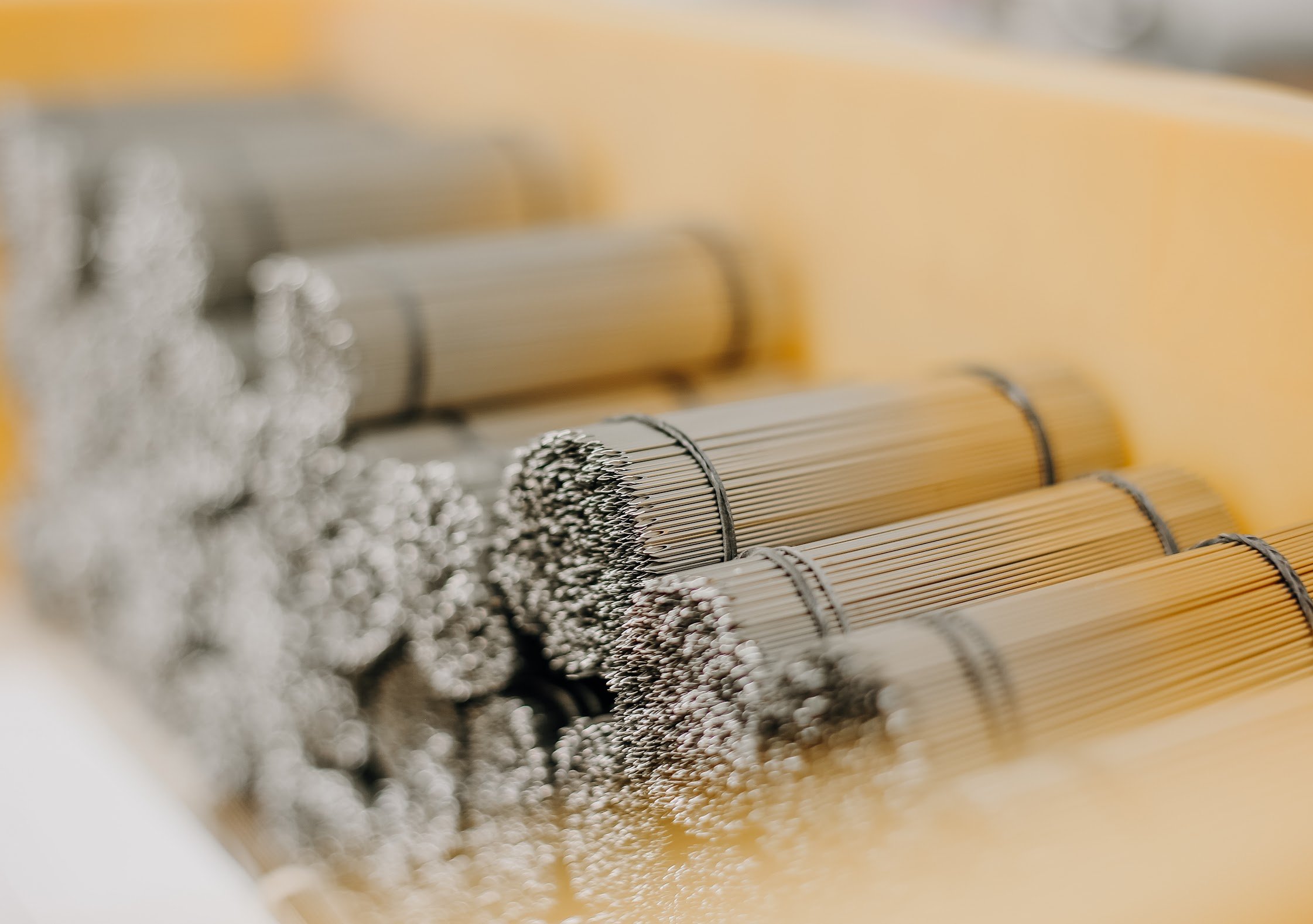 Close-up of a bundle of metal-coated wires or rods, possibly part of an industrial or mechanical component, with a blurred background.