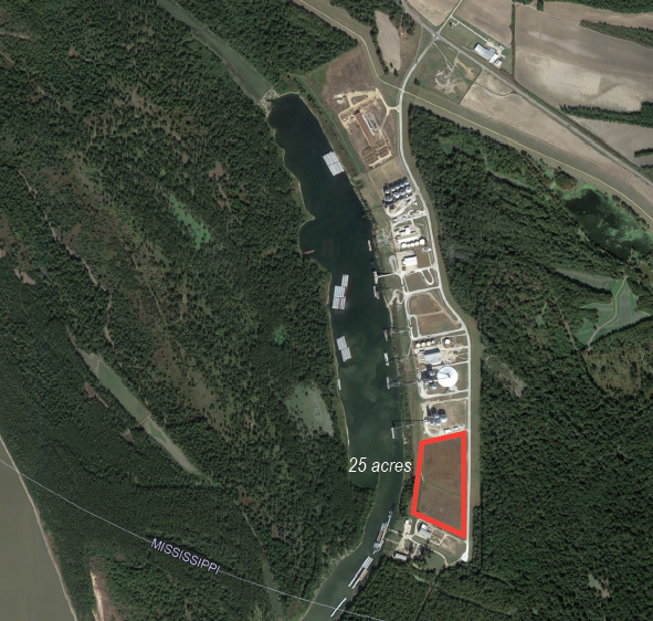 Satellite view of a 25-acre property outlined in red, located near a body of water and surrounded by dense forest, with nearby industrial and residential buildings.