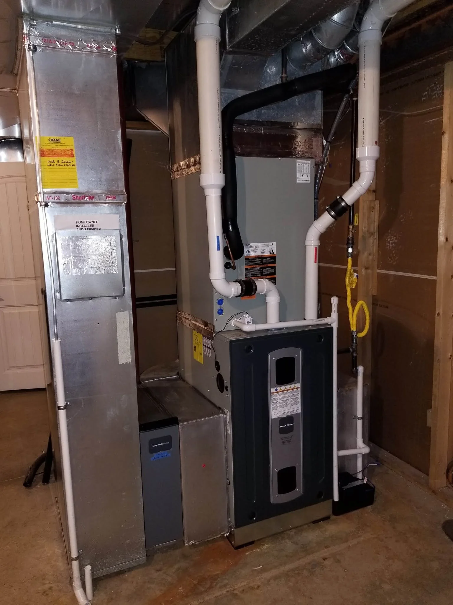 A residential HVAC system installed in a basement, including a furnace, ductwork, and pipes.