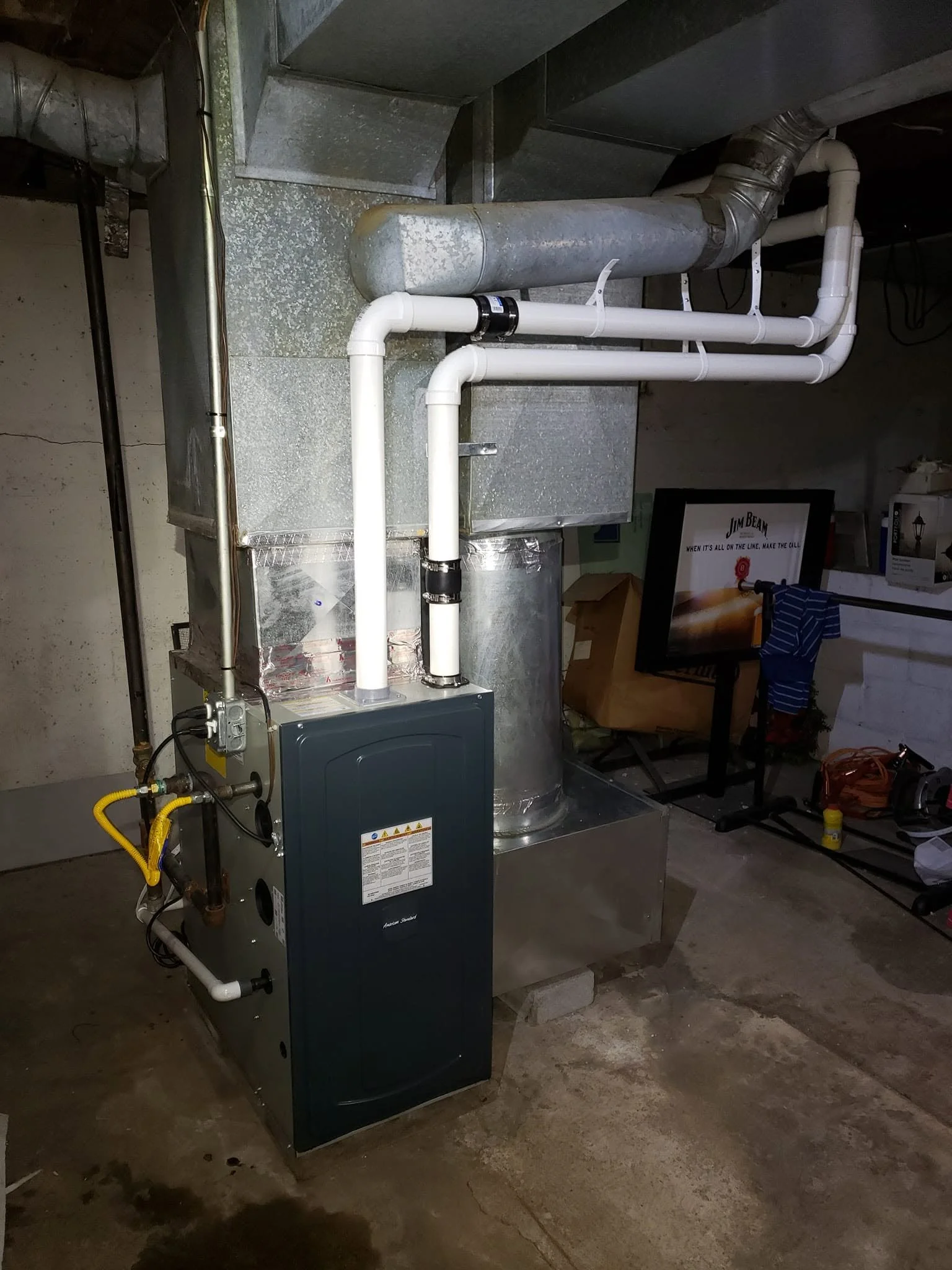 View of an HVAC system with metal ductwork and white PVC pipes in a basement setting.