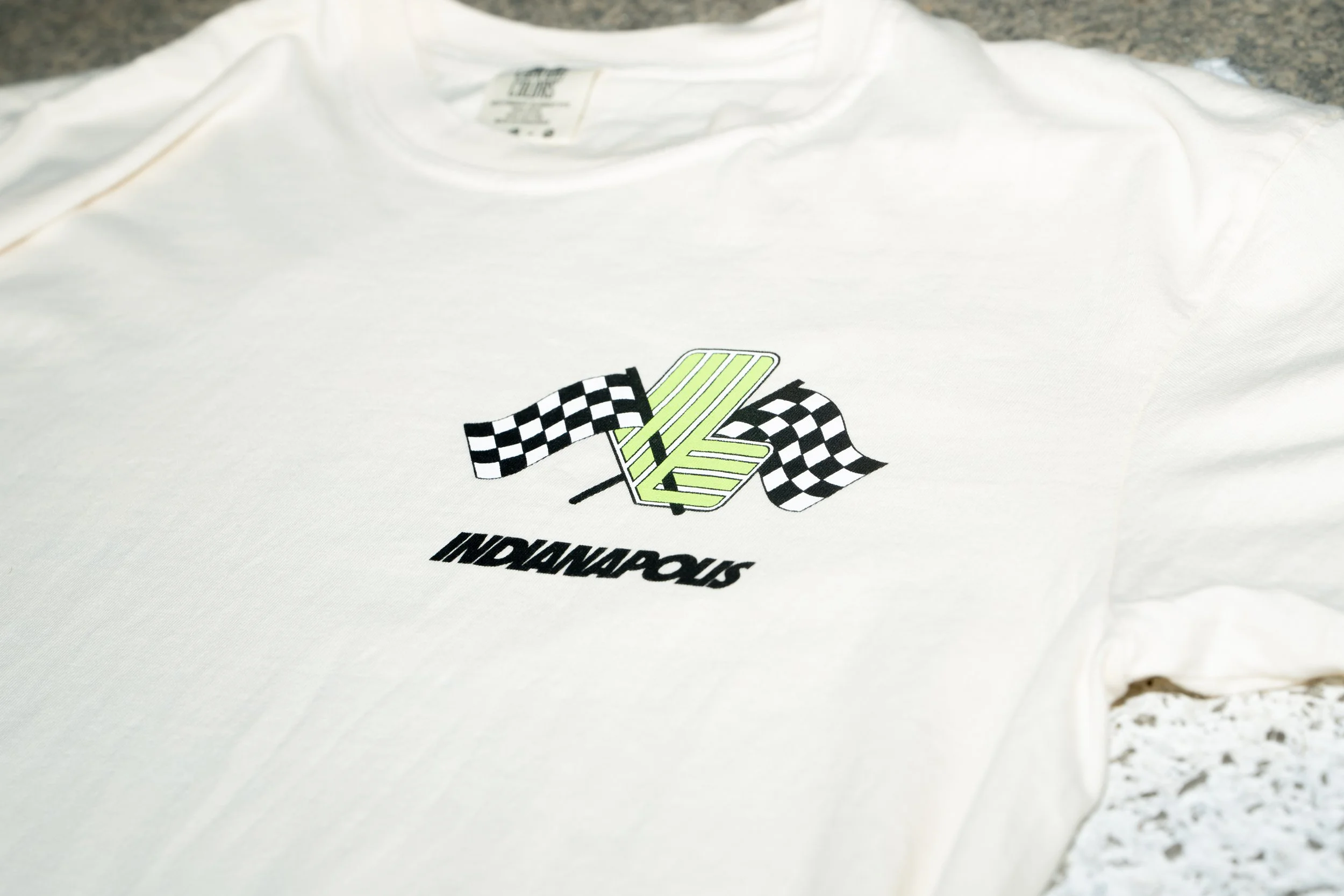 White T-shirt with NASCAR logo and checkered flag graphic on a speckled countertop.