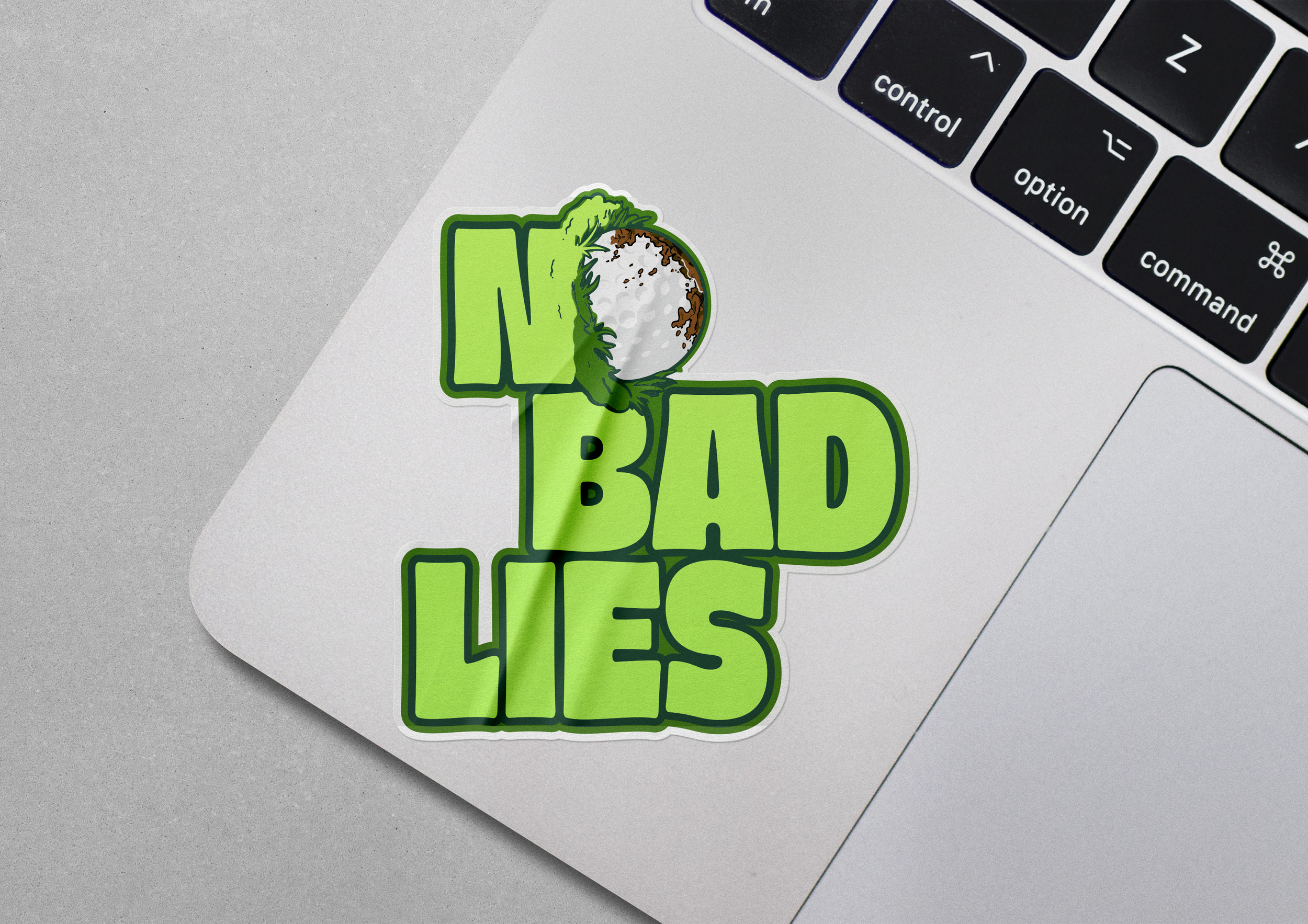 A sticker on a laptop with the phrase "I'm Badass" in green letters, featuring a small graphic of a dirt bike helmet on top of the letter 'I', located next to the keyboard.