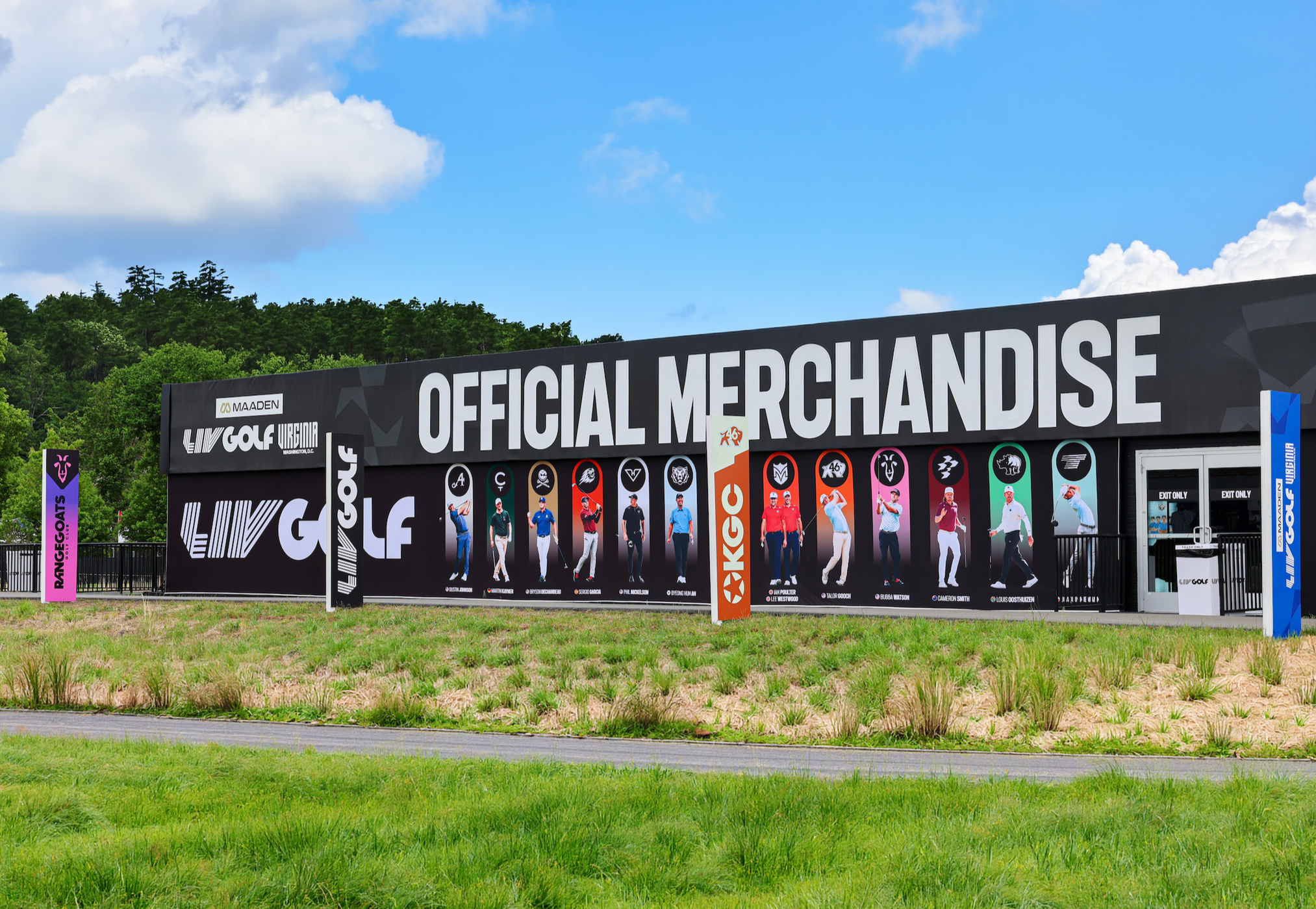 Large outdoor sign with 'Official Merchandise' and images of golf players, set against a backdrop of trees and a partly cloudy sky.