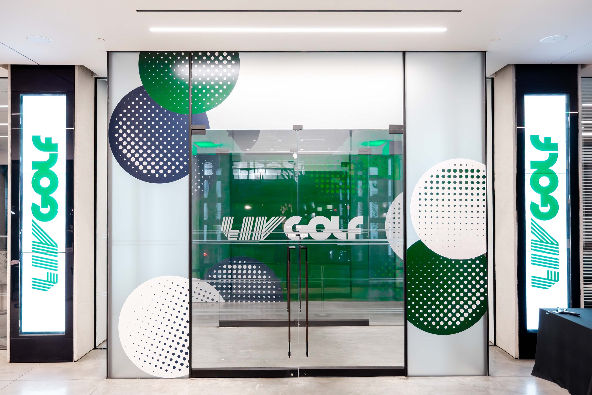 Glass doors with abstract green and black dotted circular designs, flanked by two illuminated vertical signs with green lettering spelling 'JAYCE'.