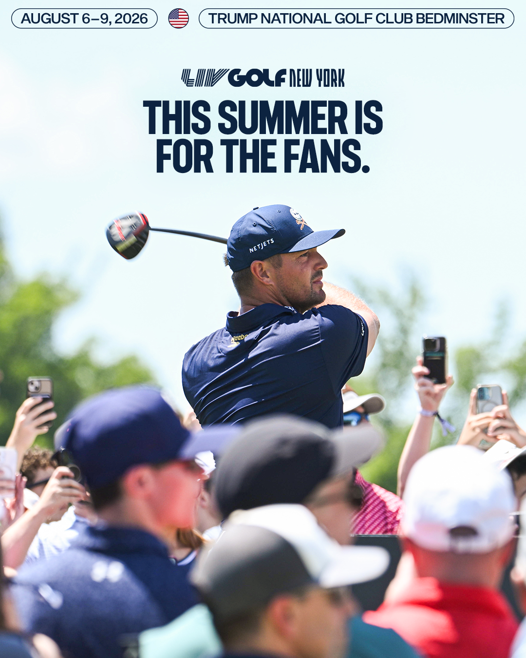 A golfer in a navy blue shirt and hat swings a golf club during a tournament at Trump National Golf Club in Bedminster, New Jersey, with spectators taking photos and watching.