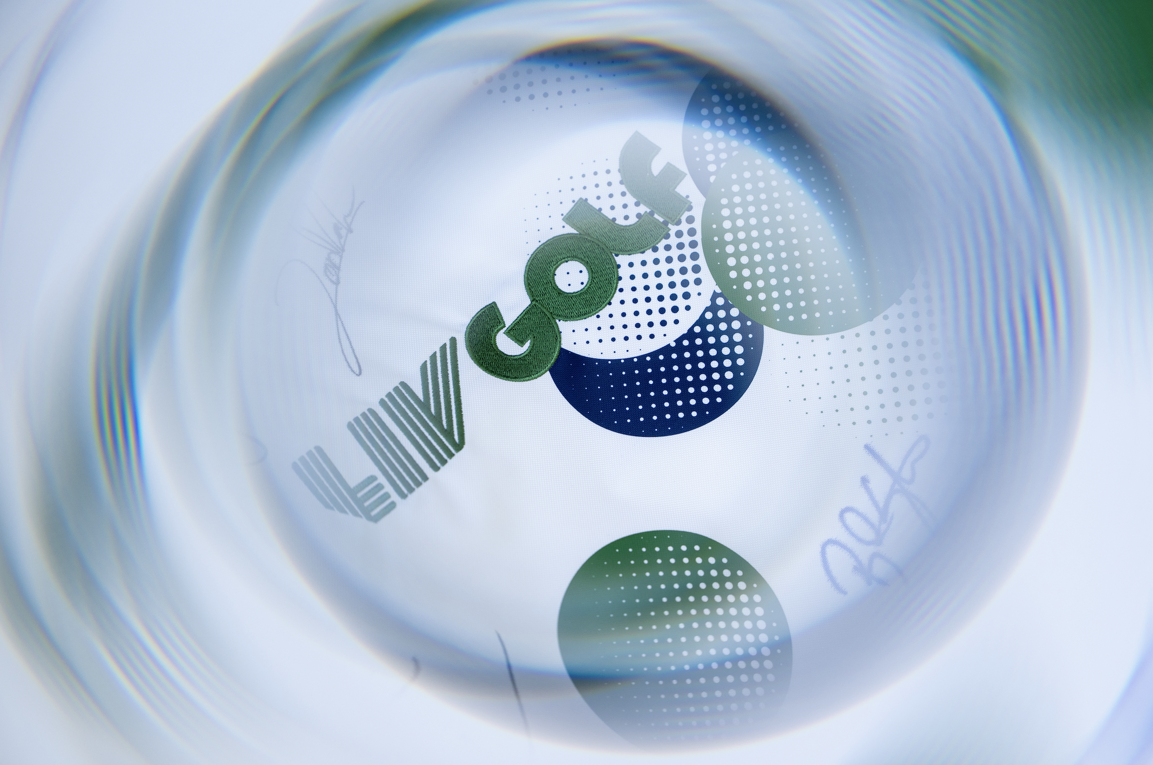 Close-up view of a glass containing a drink with a printed logo that says 'Venti' with geometric and dotted patterns in blue, green, and black colors.