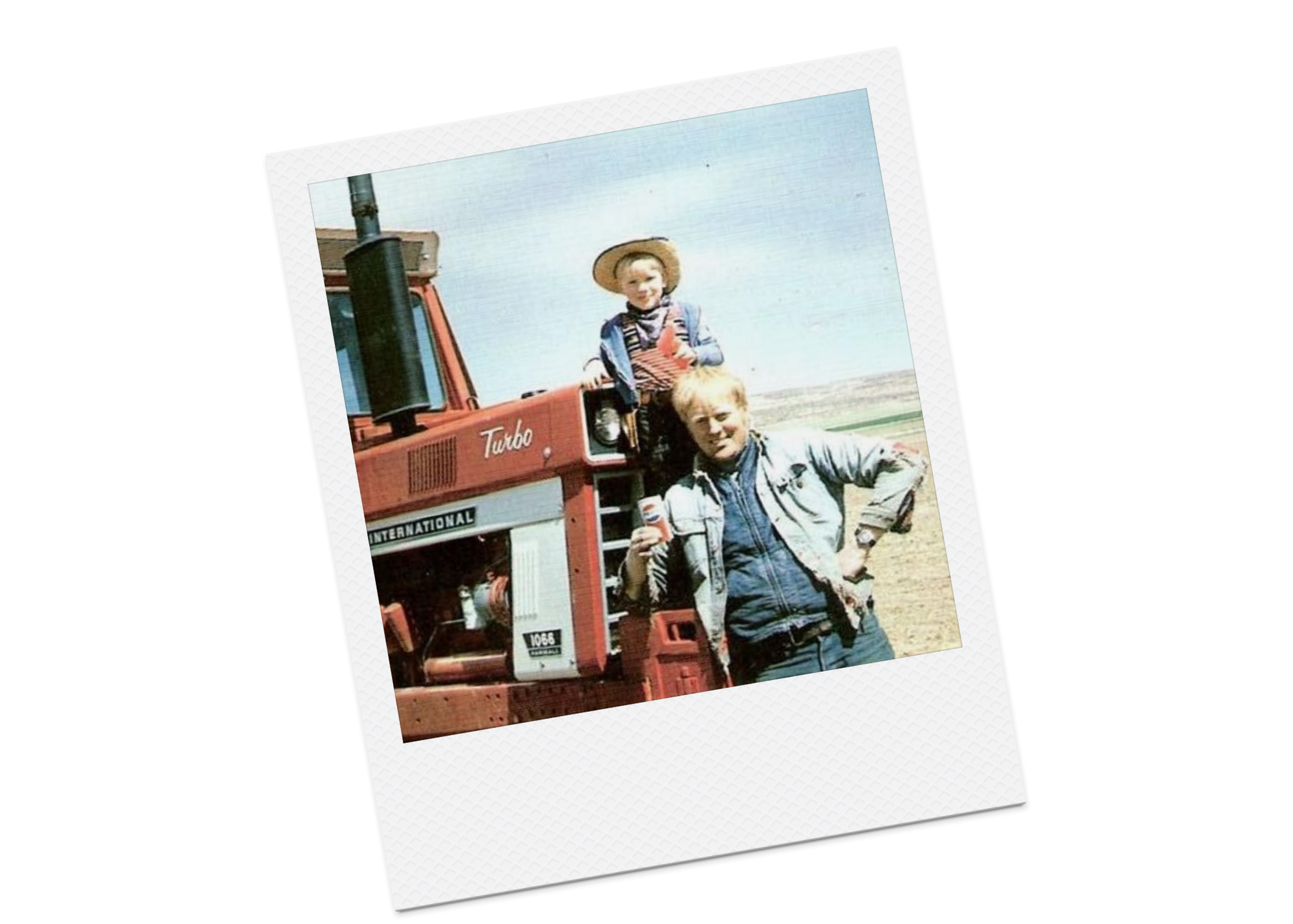 A young boy and an older man posing in front of a red tractor on a farm during the day.