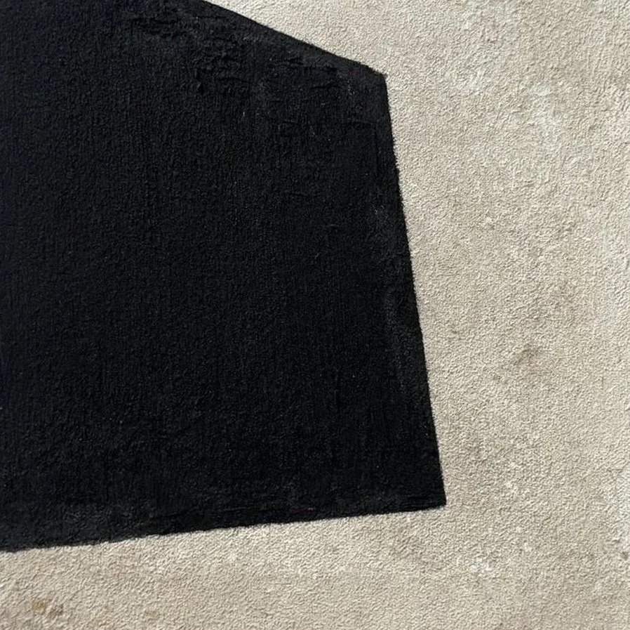 Alfombrilla negra sobre piso de cemento.