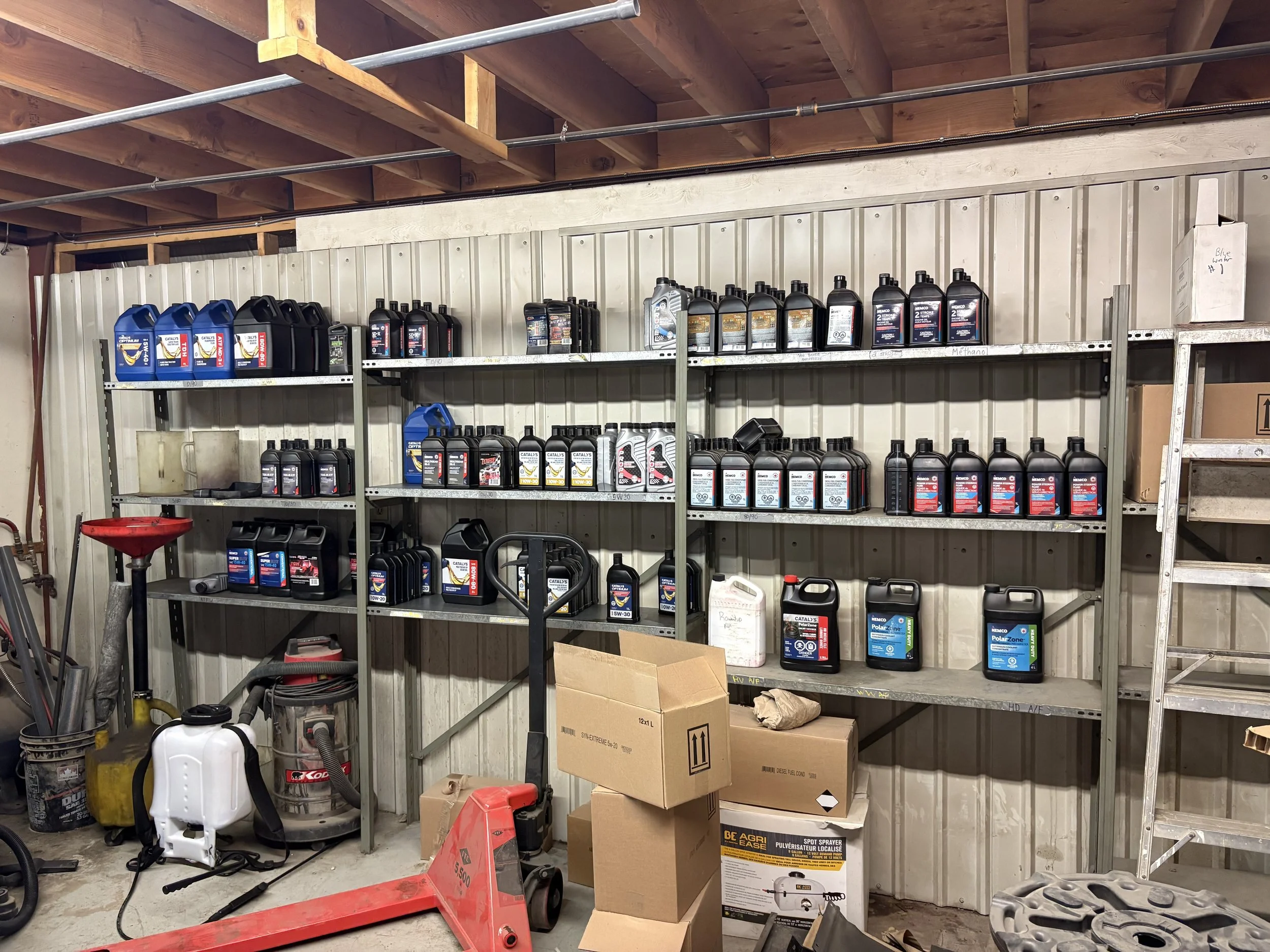 Shelves with motor oil bottles, cardboard boxes, and various tools in a garage or workshop.