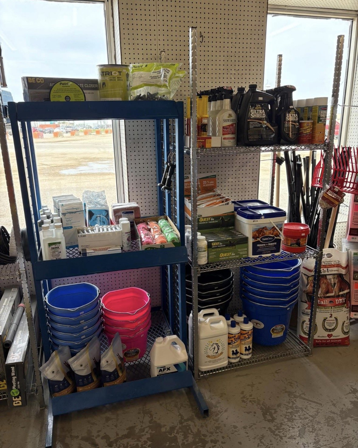 Shelving unit with various outdoor and gardening supplies, including buckets, sprays, fertilizers, and cleaning products, at a store.