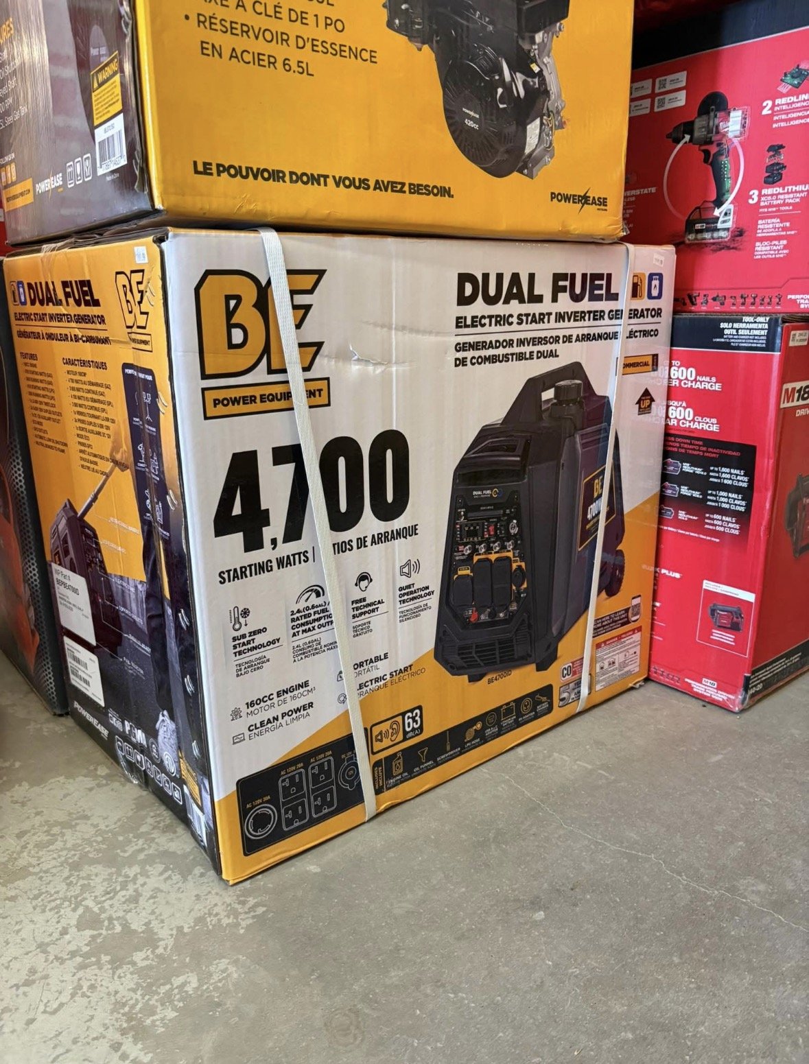 Boxed B EZ dual fuel electric start inverter generator with 4700 starting watts, placed on a store floor among other boxed power tools.