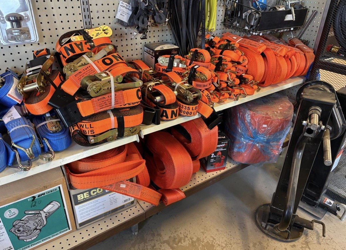 Shelving with orange and blue ratchet straps and lifting equipment in hardware store.