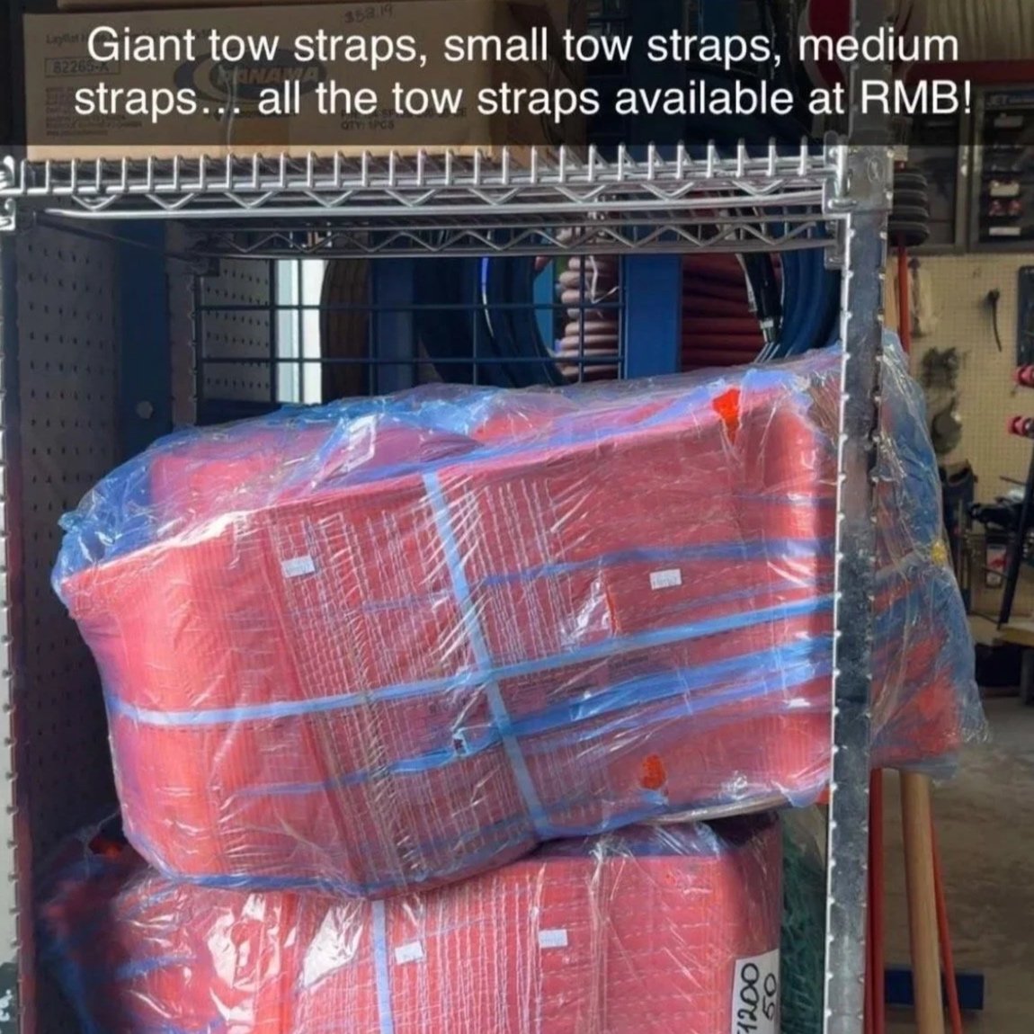 Stack of orange tow straps wrapped in clear plastic on a metal shelf in a hardware store.
