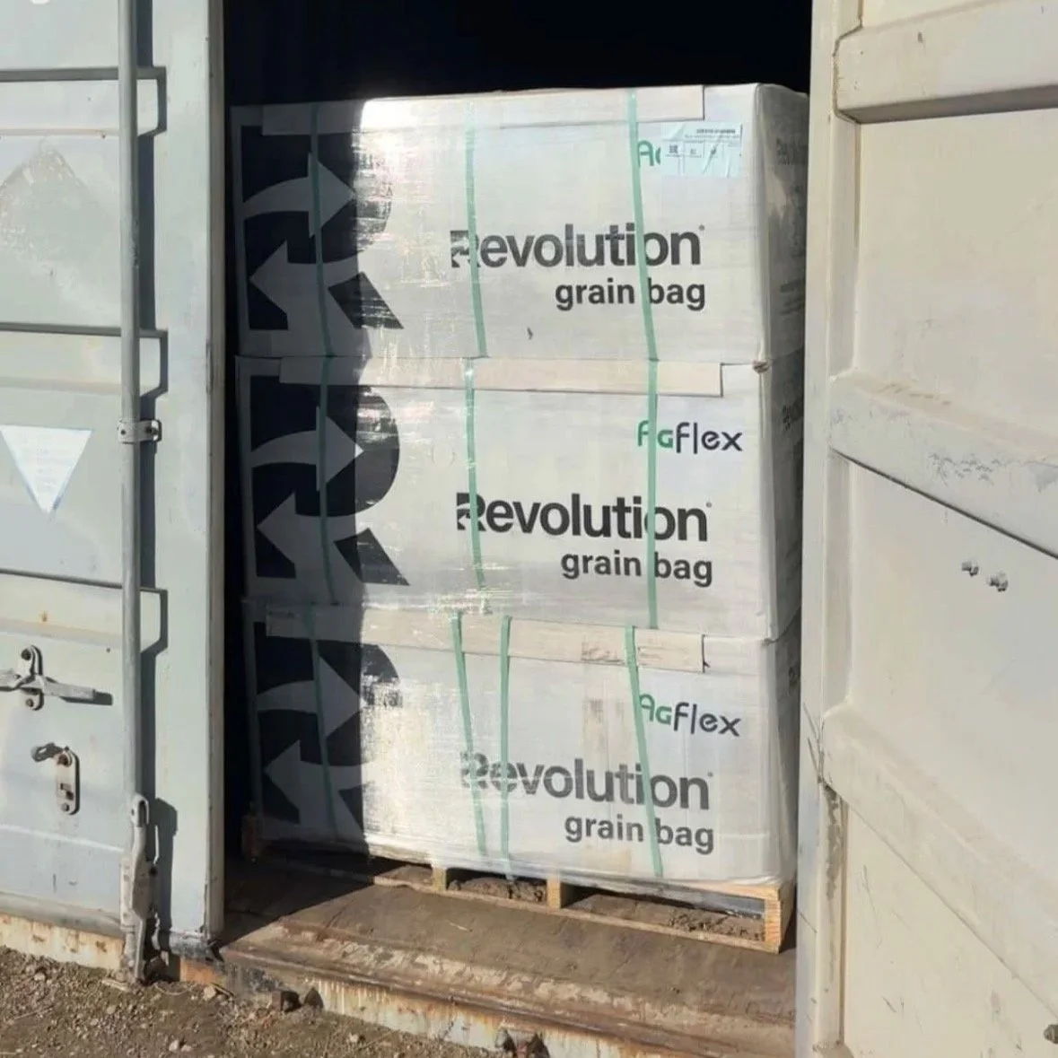 Three large boxes labeled 'Revolution grain bag' stacked on a pallet inside a shipping container.