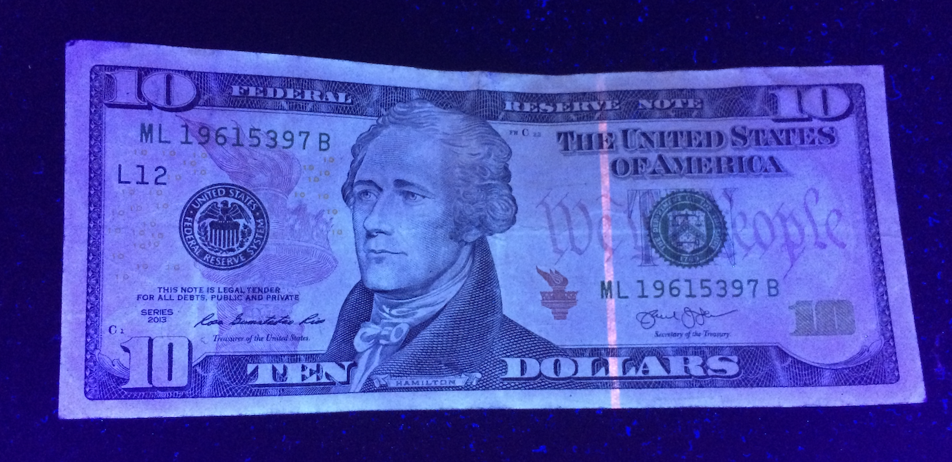 A ten-dollar bill illuminated under blue light.