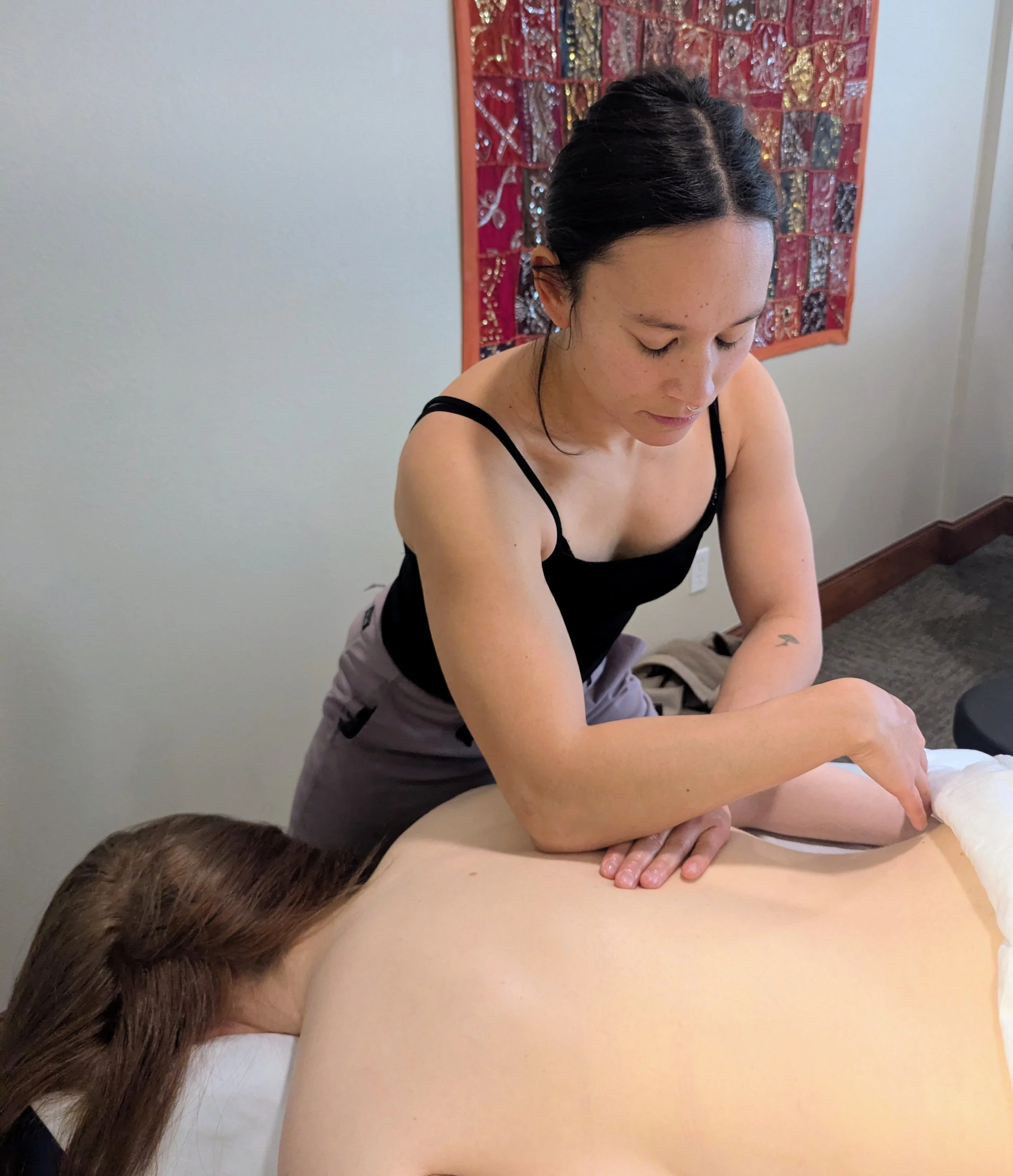 A woman receiving a massage from a massage therapist in a wellness center.