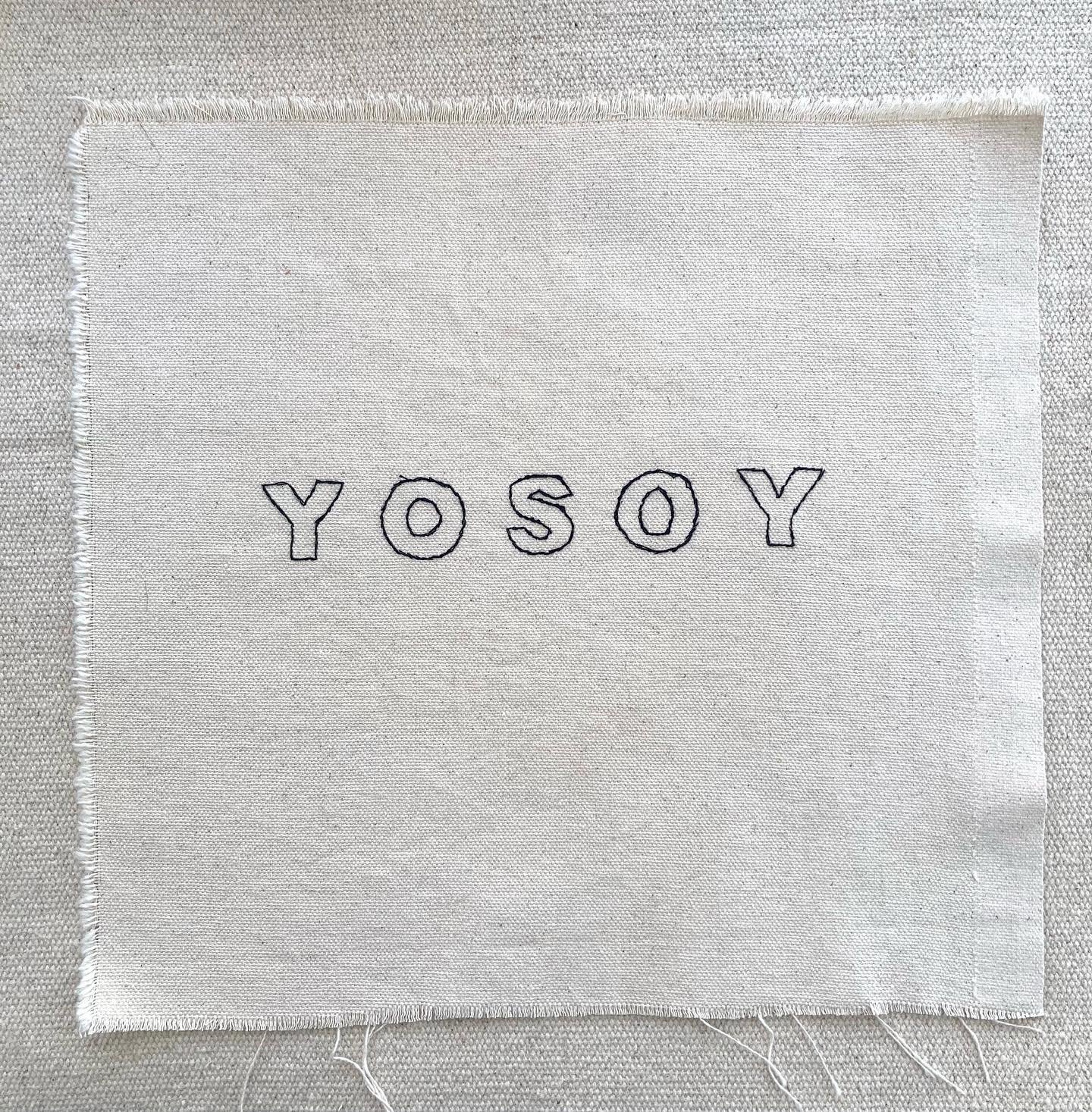 Obra de arte contemporanea de etiqueta de tela blanca con la palabra 'YOSOY' bordada en letras negras.
