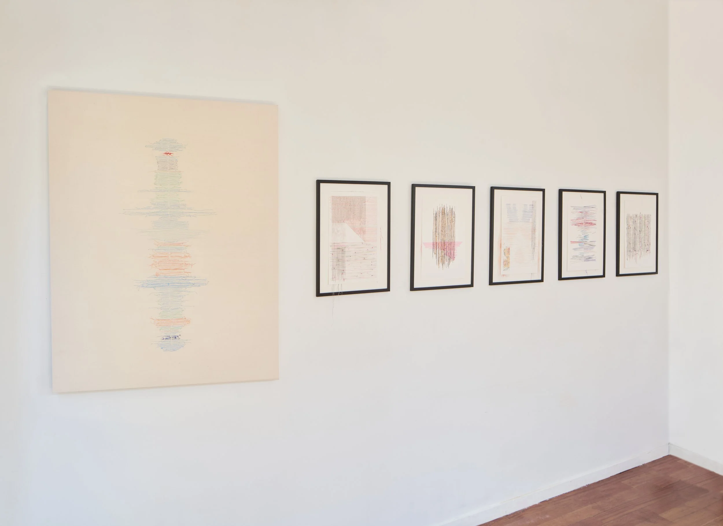 Galería de arte con seis cuadros abstractos enmarcados en negro en una pared blanca, un cuadro grande a la izquierda y cinco cuadros más pequeños en línea a la derecha.