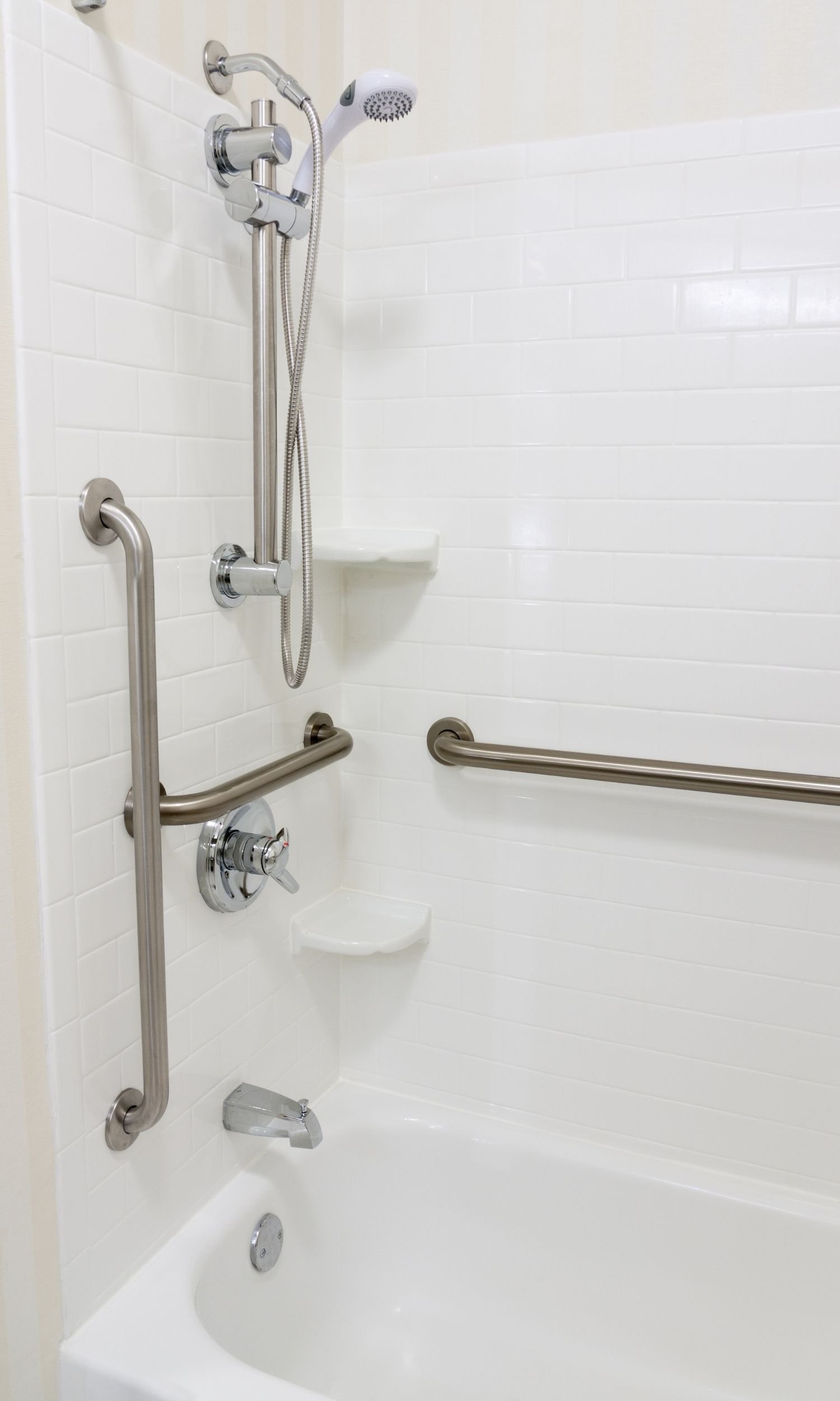 Accessible bathtub modification featuring stainless steel grab bars and handheld showerhead installation completed by Melesh Construction Dallas serving the DFW Metroplex