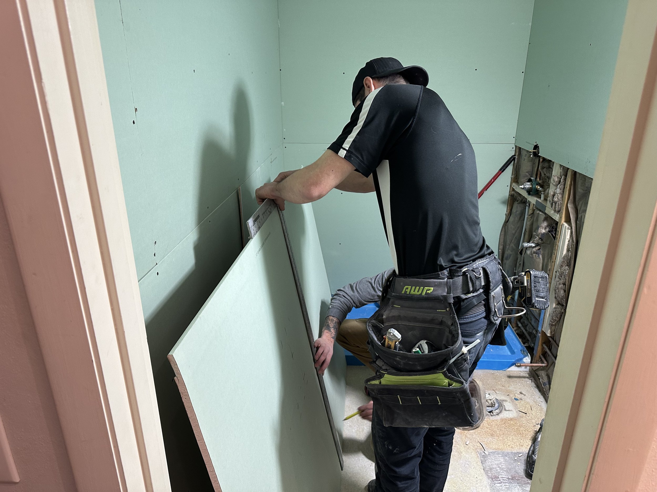 Melesh Construction Dallas crew members installing drywall during a bathroom accessibility renovation project in the Dallas Texas area