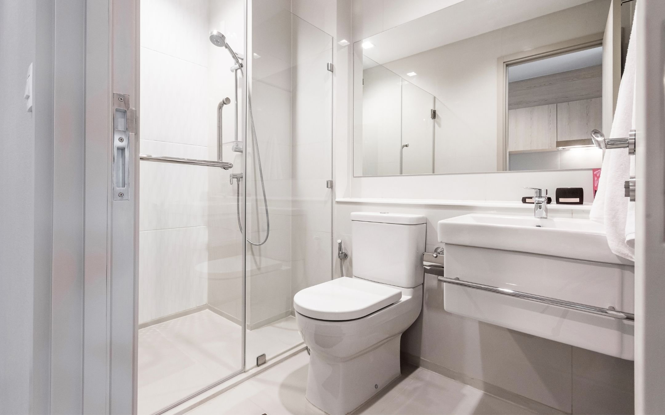 Accessible bathroom renovation featuring roll-in shower with grab bar, glass door, floating vanity, and wide-clearance layout completed by Melesh Construction Dallas