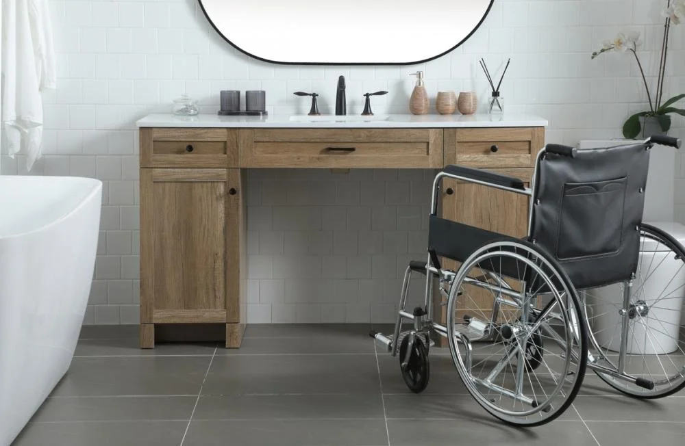 Wheelchair positioned at accessible bathroom vanity with open knee clearance and wide floor space representing bathroom modification work by Melesh Construction Dallas