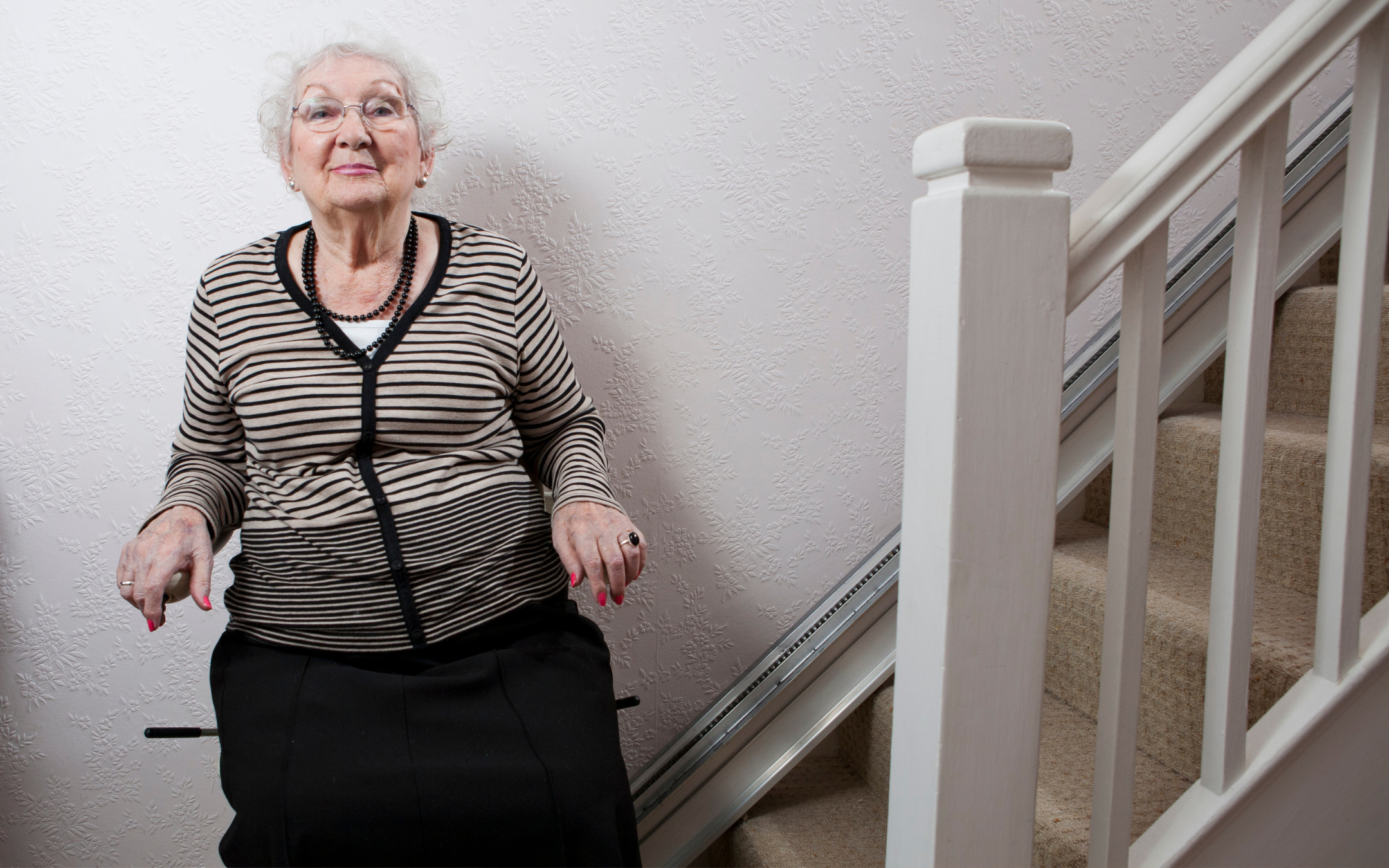 Senior woman using residential stairlift installation representing aging-in-place home accommodation work by Melesh Construction Dallas serving the DFW Metroplex