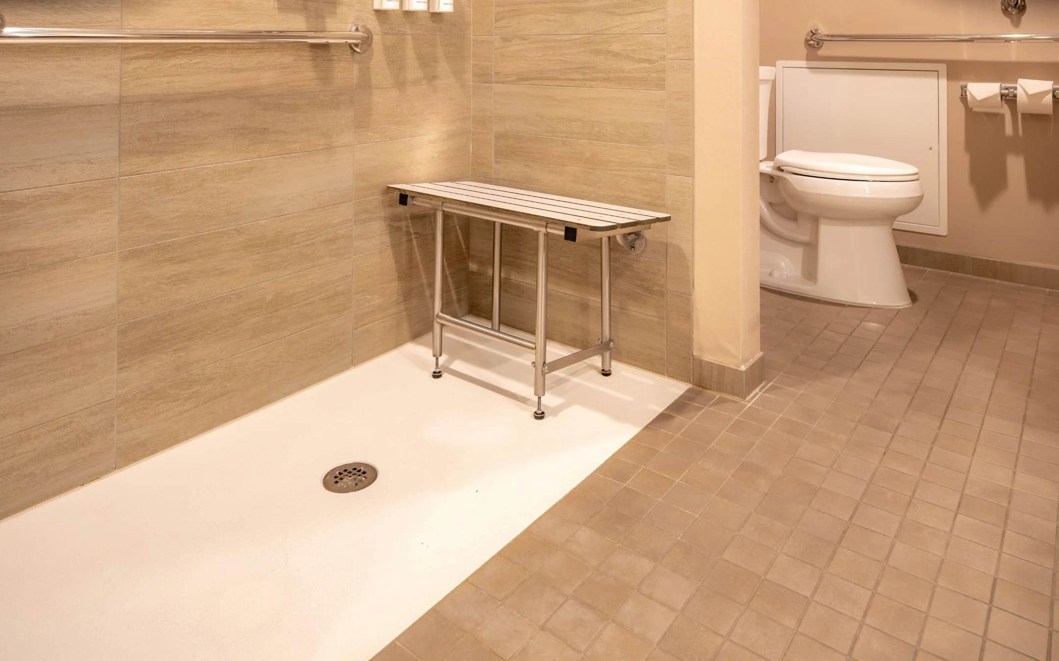 Accessible roll-in shower with fold-down bench, stainless grab bars, curbless entry, and comfort height toilet installed by Melesh Construction Dallas serving the DFW Metroplex