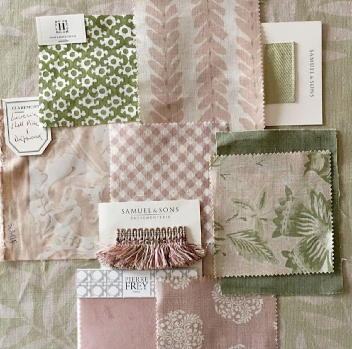 Swatches of fabric in pastel shades, including pink, green, and beige, with floral and geometric patterns, along with fabric samples, sample cards, and a decorative tassel.