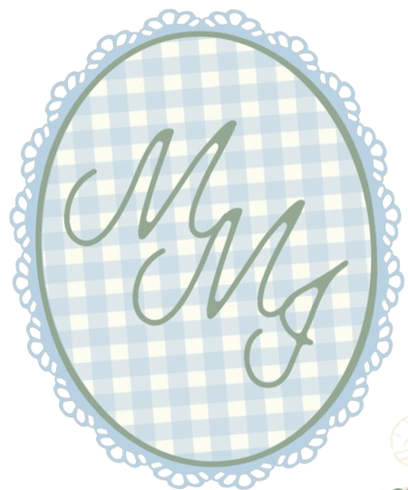 Oval-shaped decorative sign with a light blue and white checkered background, featuring the initials "M M" in elegant script, surrounded by a lace-like border.