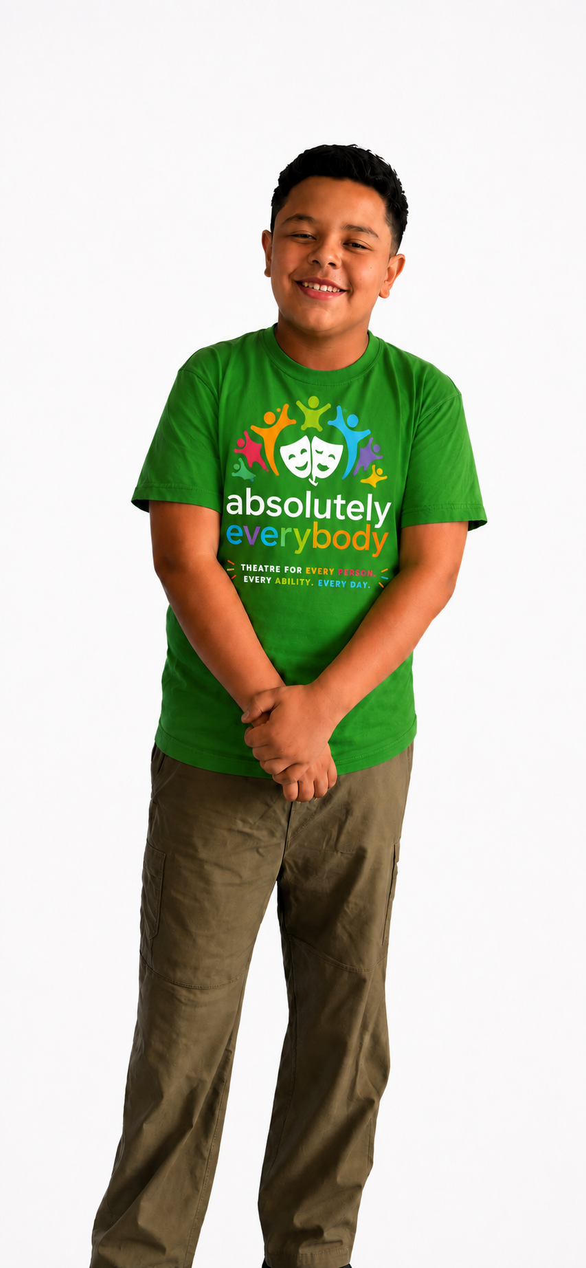 A young boy with short dark hair smiling, wearing a green T-shirt with colorful text and graphics and khaki pants, standing against a plain white background.