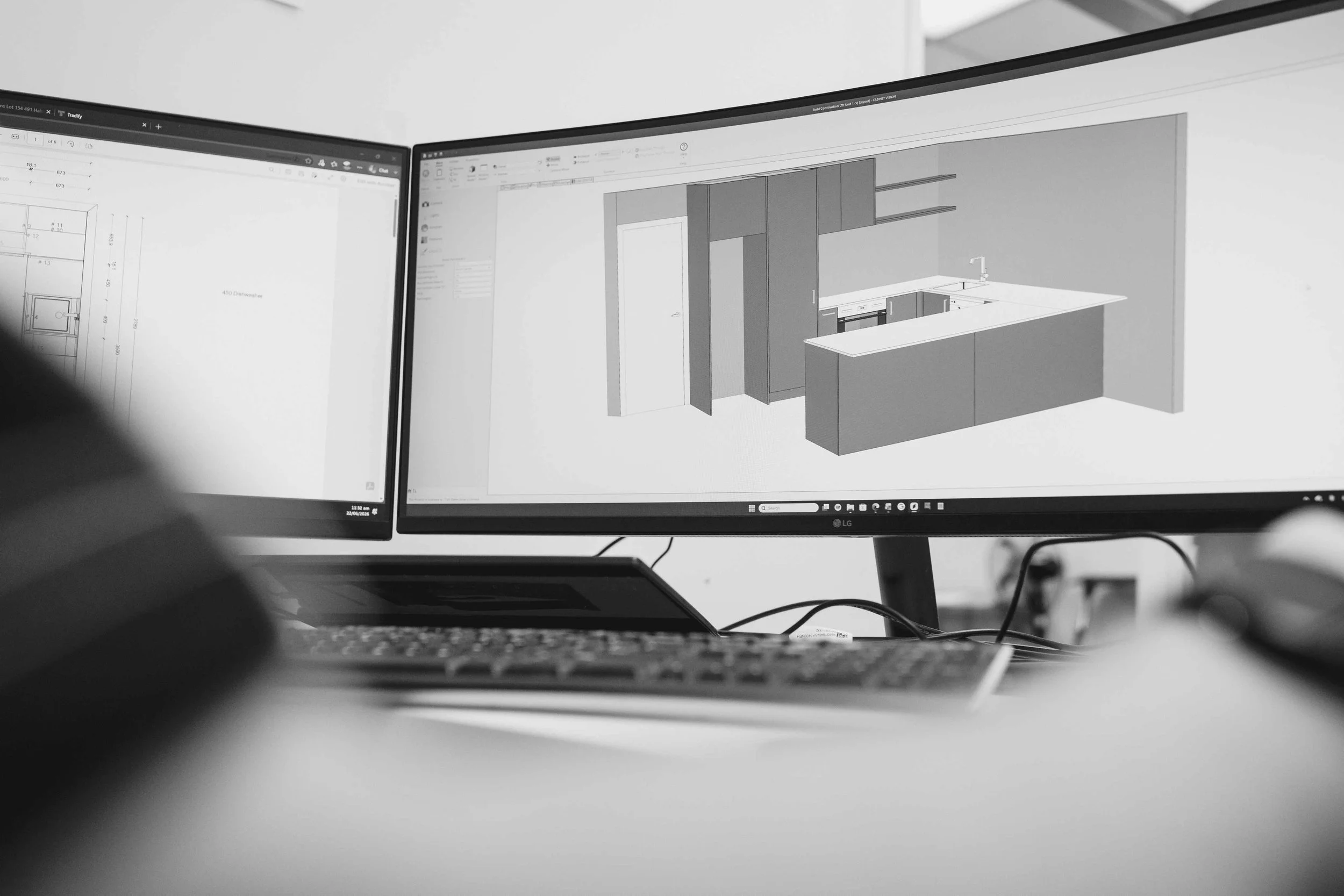 Two computer monitors displaying architectural design plans and a 3D kitchen model, viewed from a desk with a keyboard in the foreground.