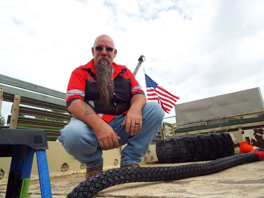 Gabe squatting on 5ton, American flag in background