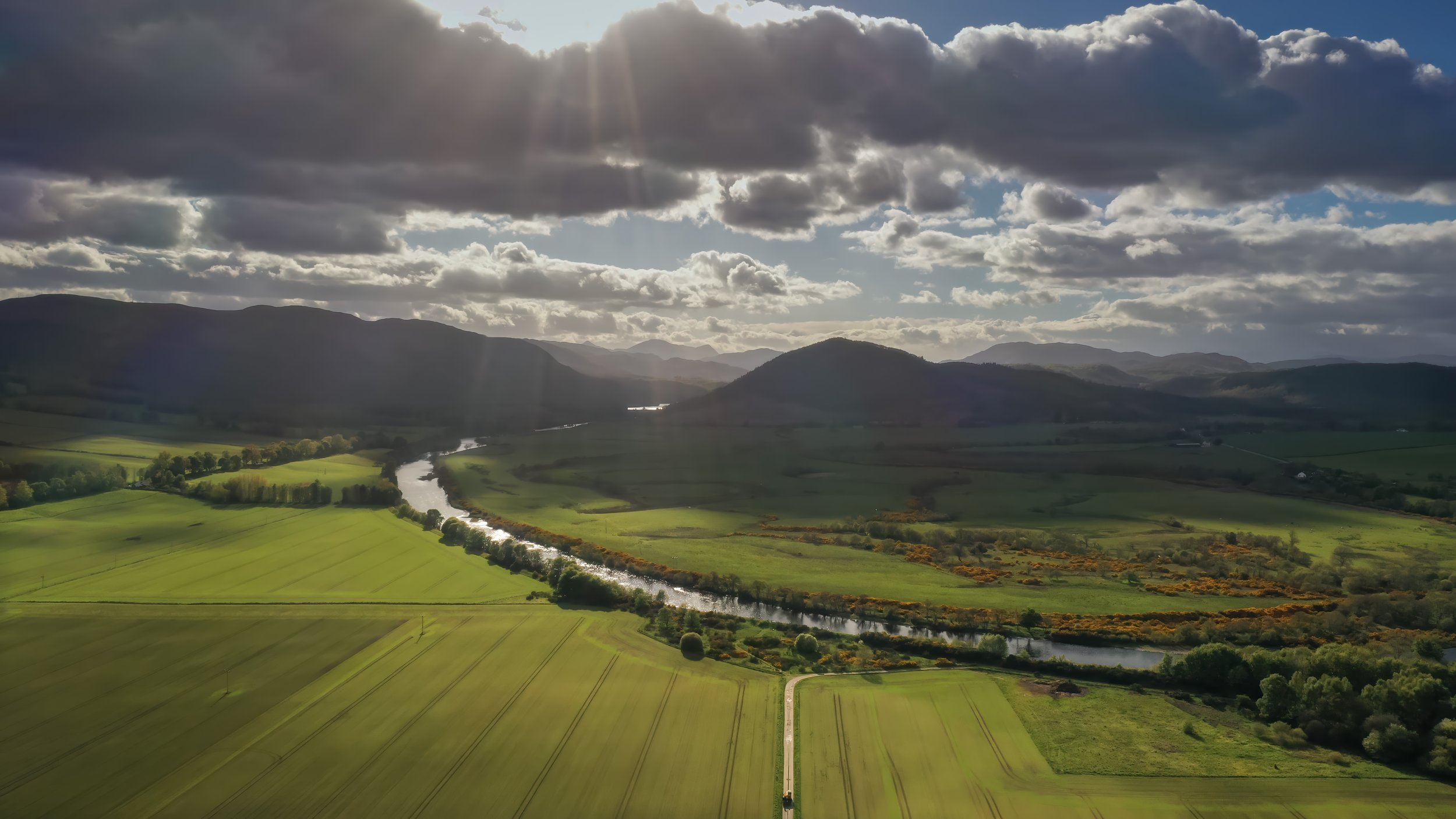Aerial photo of Strath Conan with the light breaking through the clouds over moody hills and the River Conan