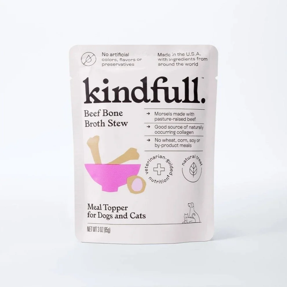 Packaging for kindfull beef bone broth stew for dogs and cats, featuring a pink bowl with two bones inside, and text highlighting natural ingredients, no artificial colors or preservatives, and vet guidance.