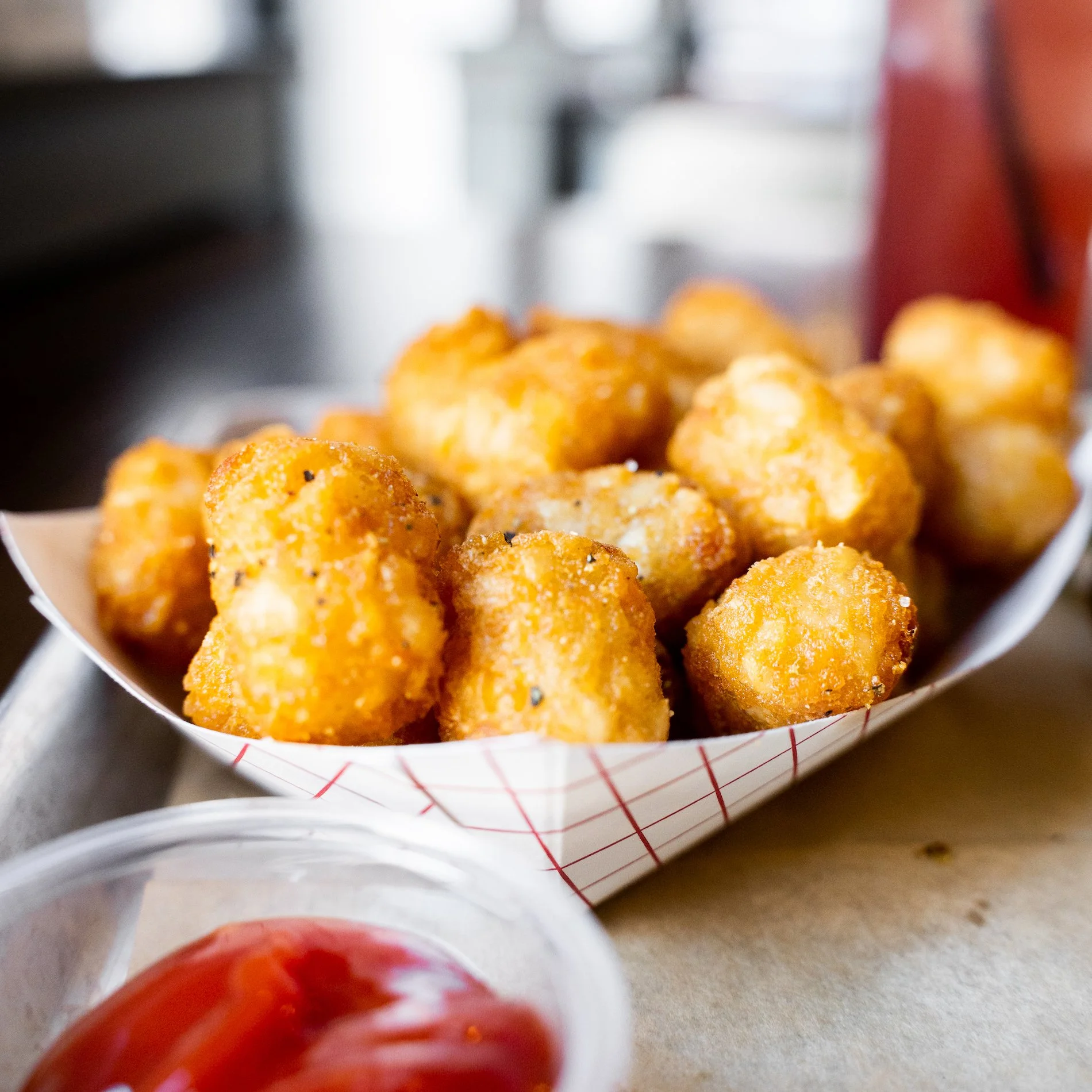 Close-up of golden, seasoned popcorn chicken in a paper food tray with red and white checkered pattern.