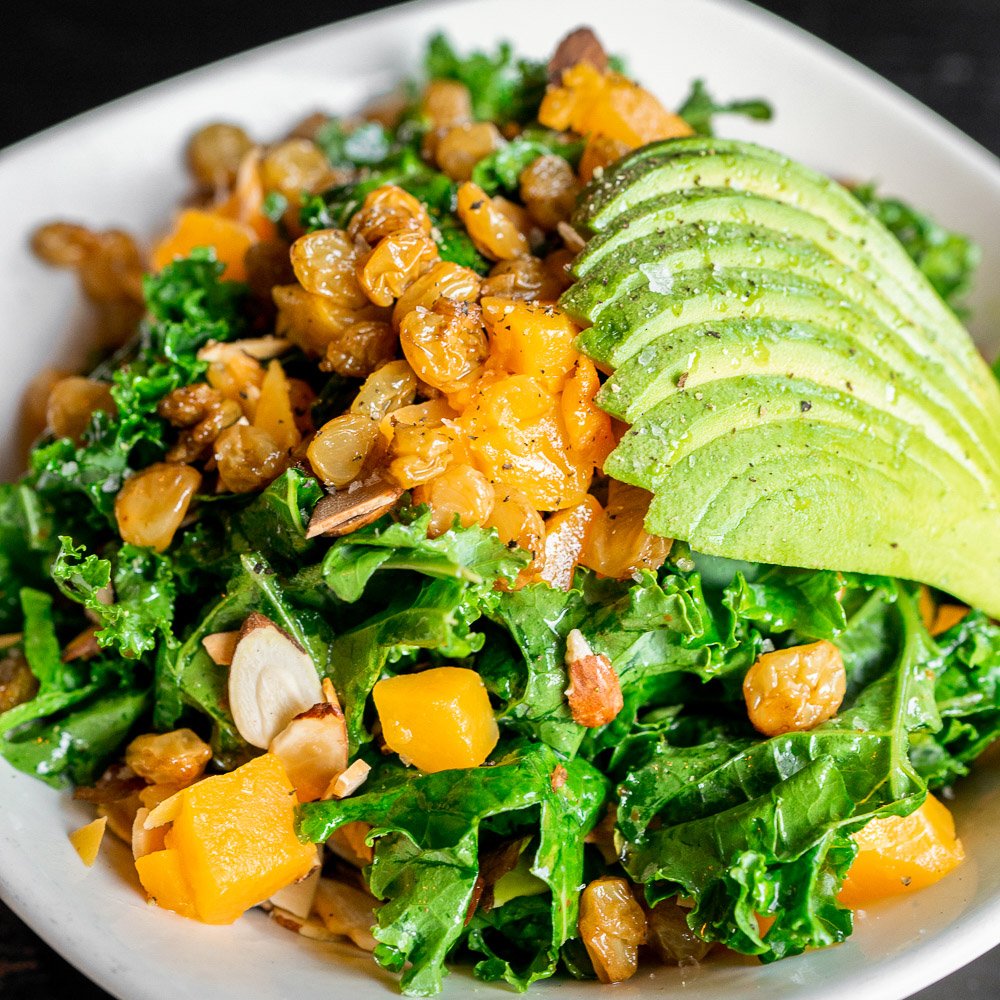 Salad with kale, chopped mango, avocado slices, roasted chickpeas, and sliced almonds.