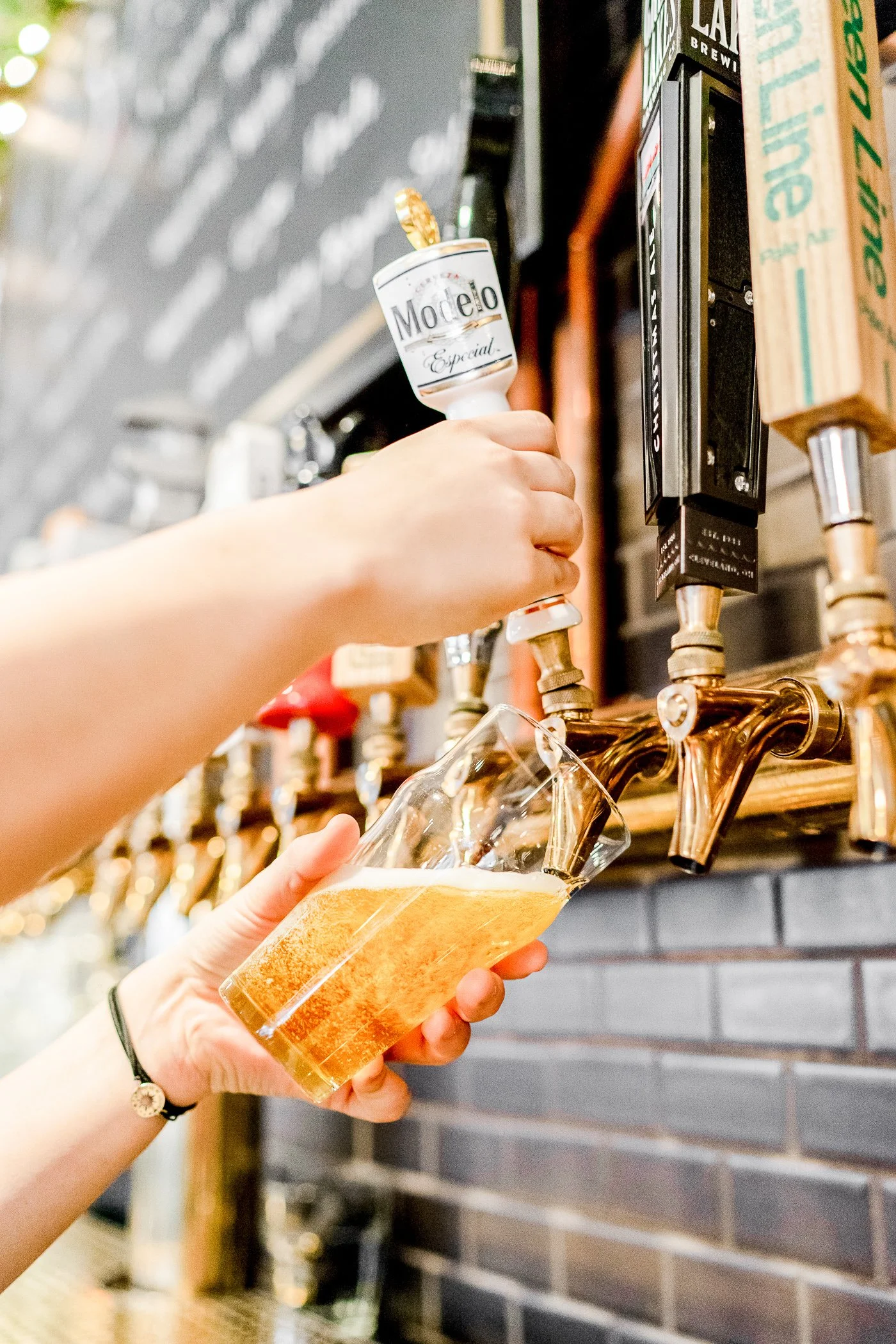 Person pouring draft beer from tap into glass at bar