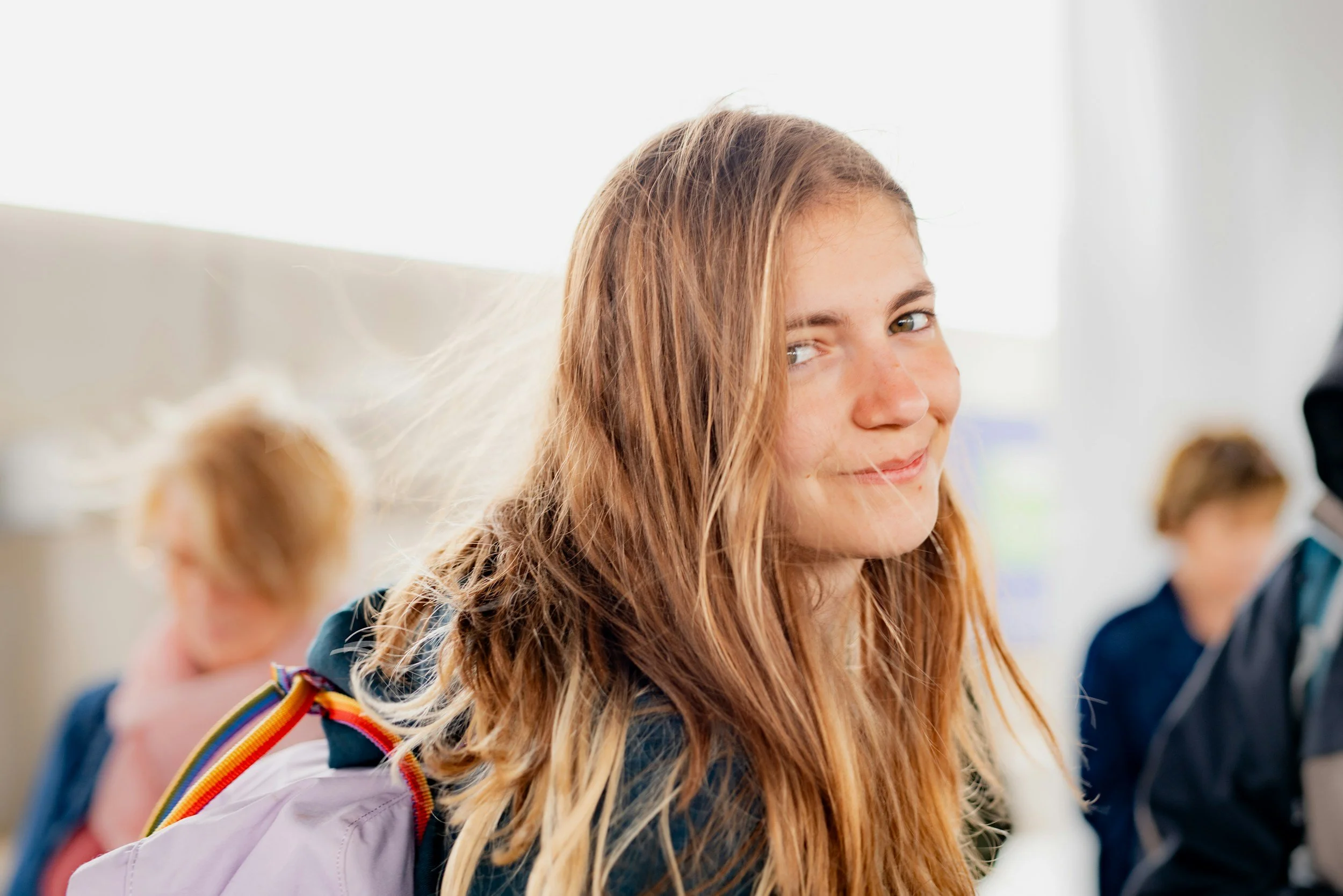 Smiling student with a backpack at school, ready to talk with a trusted teacher