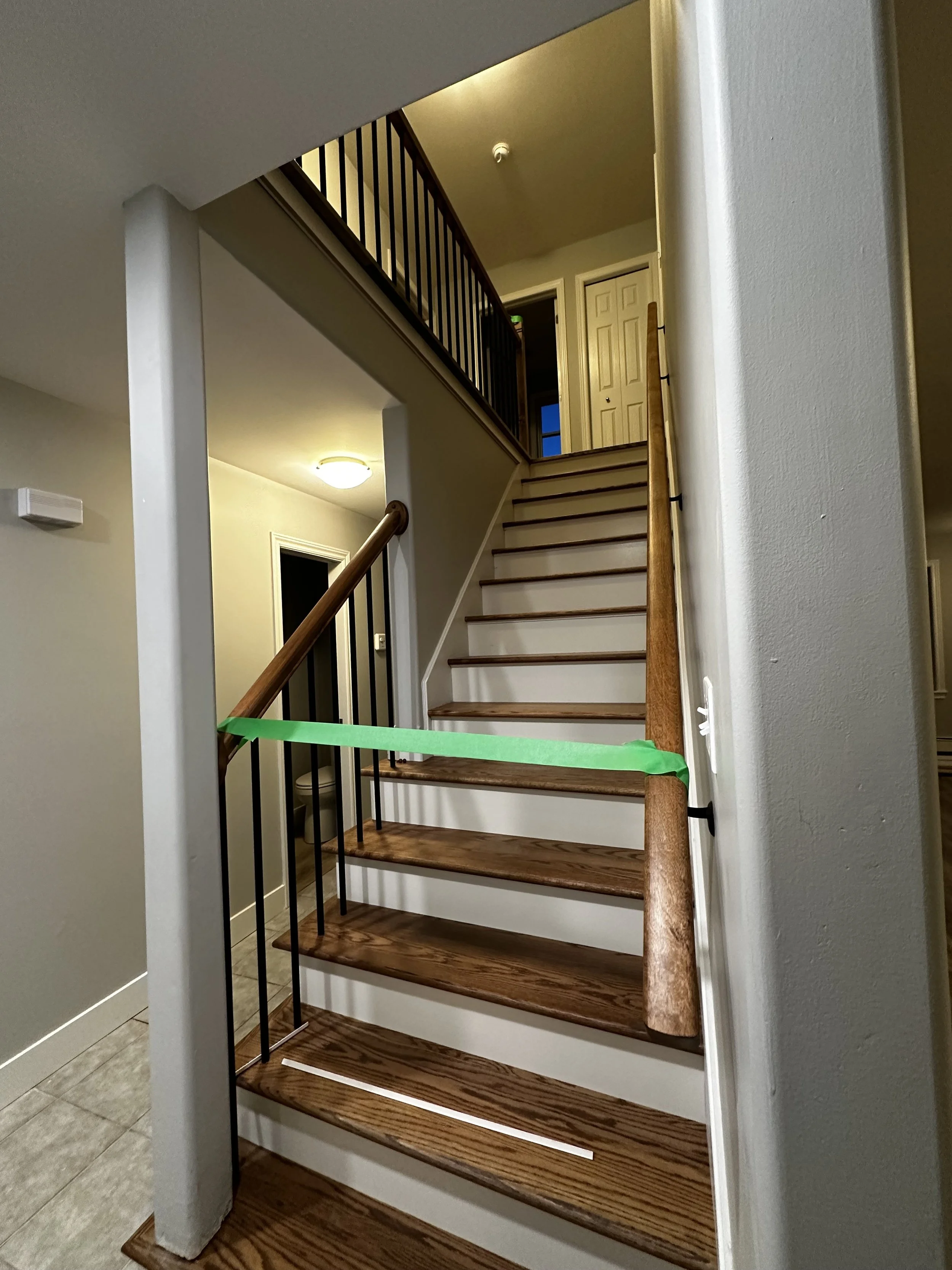 A staircase with wooden steps, a wooden handrail, and black metal balusters in a residential interior.