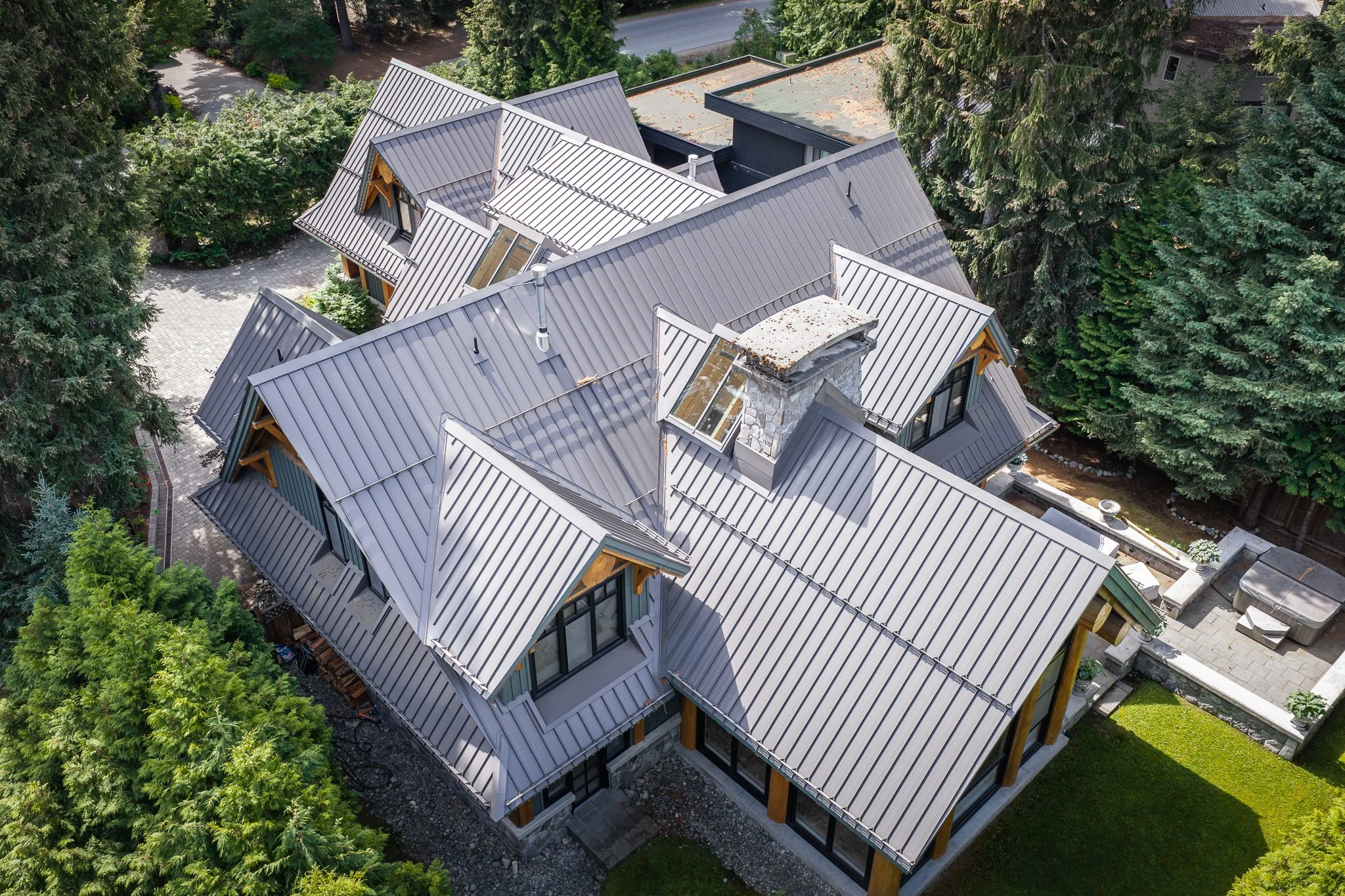 Aerial view of a luxury home in Whistler featuring a standing seam metal roof designed for mountain living.