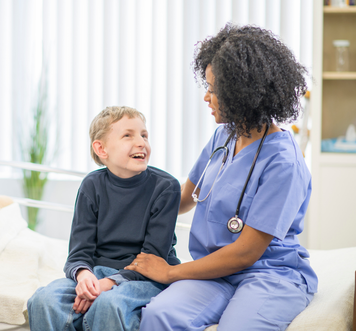 A young boy smiling and talking with a female nurse