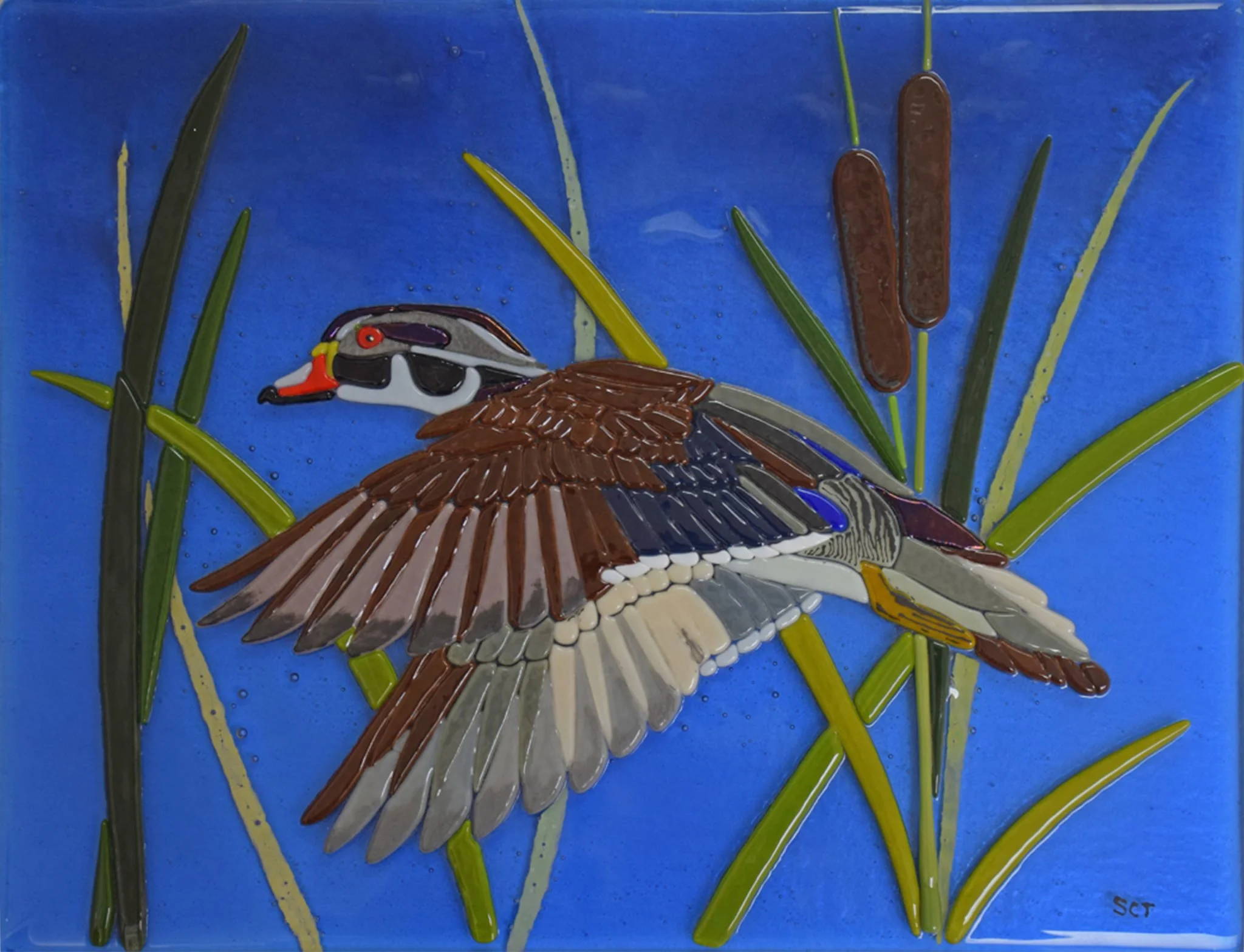 Glass mosaic artwork depicting a duck with a white head, orange beak, and brown and gray body, set against a bright blue background with green reeds and cattails.