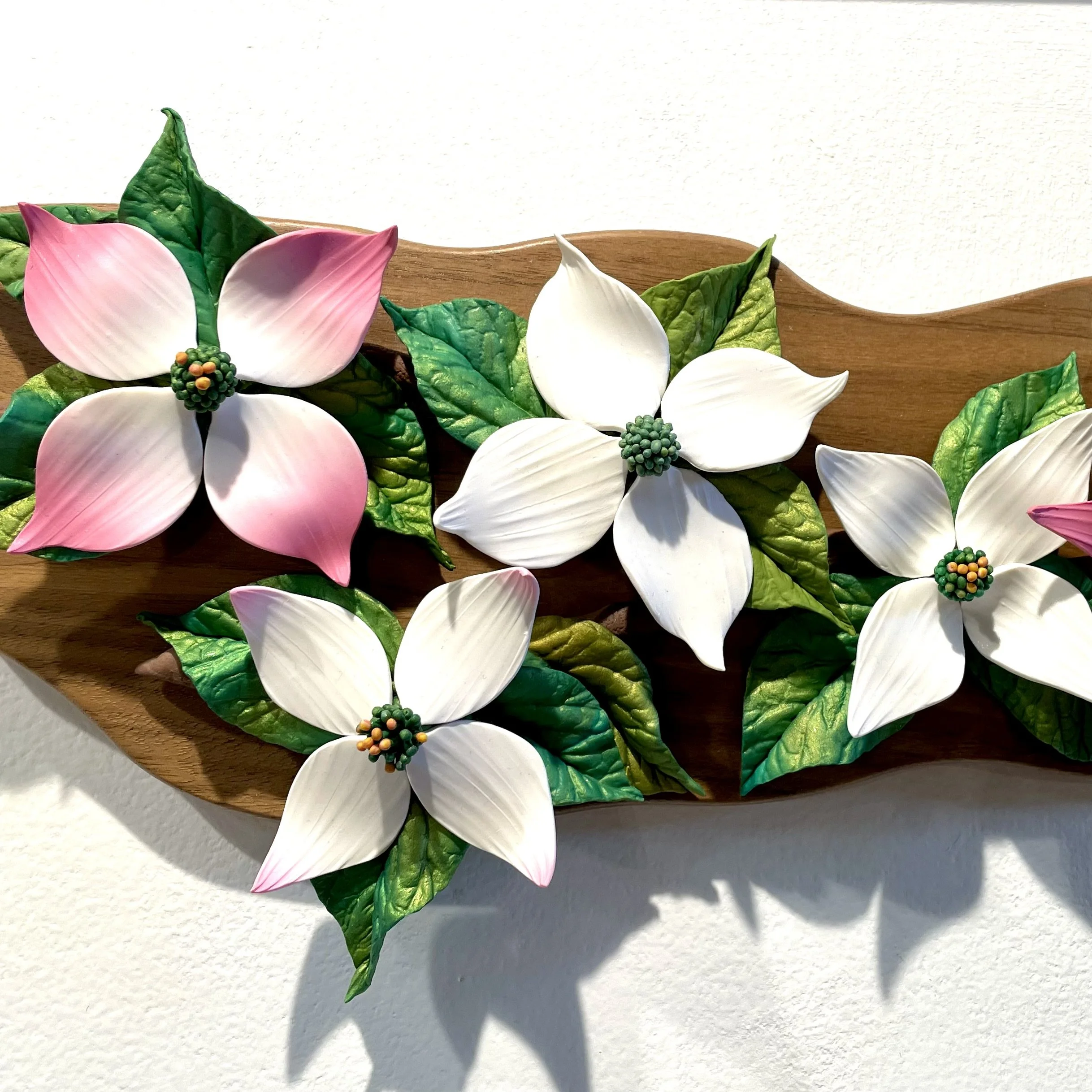 Decorative flower arrangement with pink and white flowers and green leaves on a wooden surface.