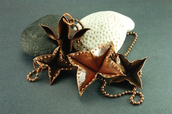 Decorative metallic starfish and seashell jewelry on rocks and a white coral piece