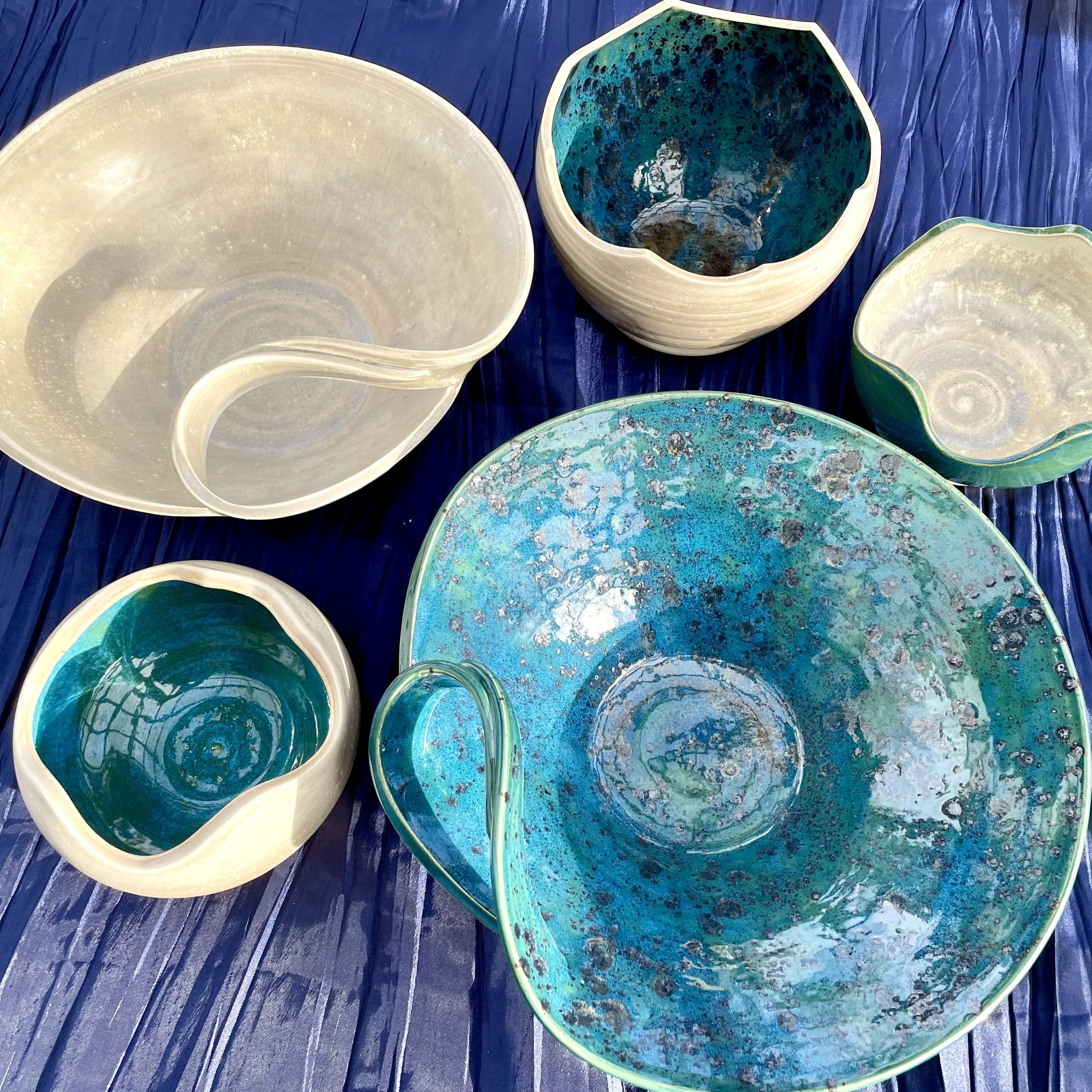 Several decorative bowls with blue, green, and white marbled patterns placed on a dark wooden surface.