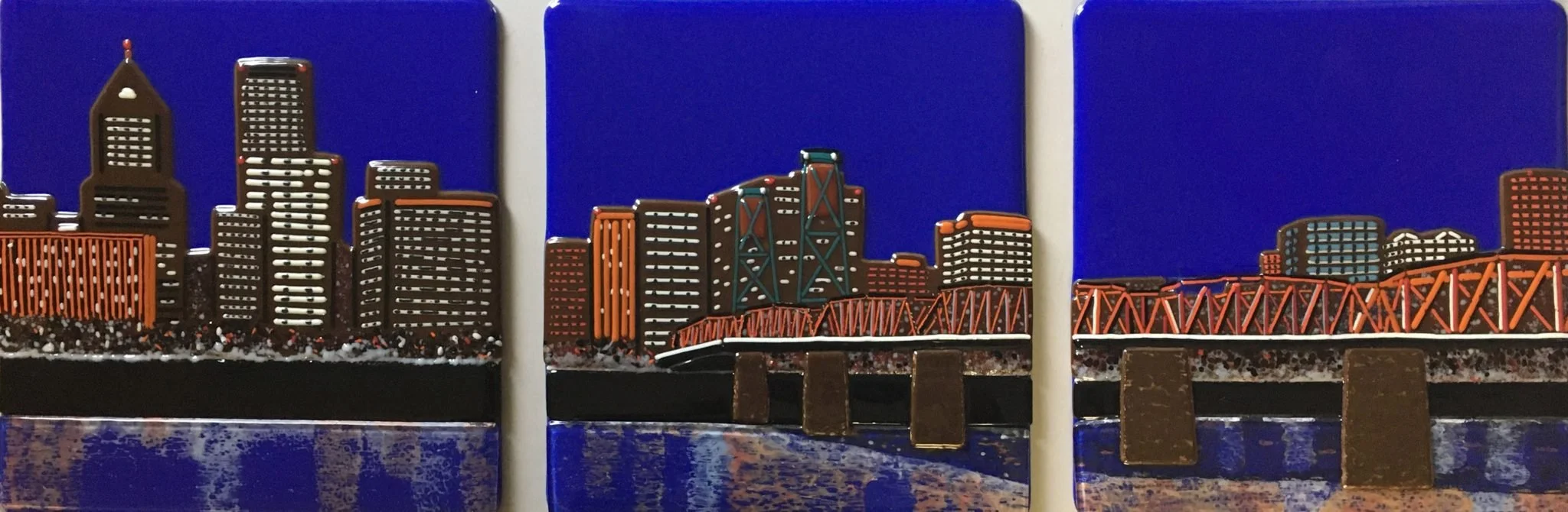 Colorful artwork depicting a city skyline with tall buildings, a bridge, and water, on a series of three connected blocks.