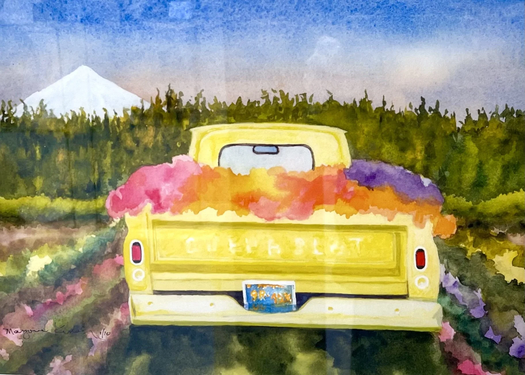 Watercolor painting of a yellow truck, loaded with colorful flowers, driving on a rural road with green trees, a mountain, and a partly cloudy sky in the background.