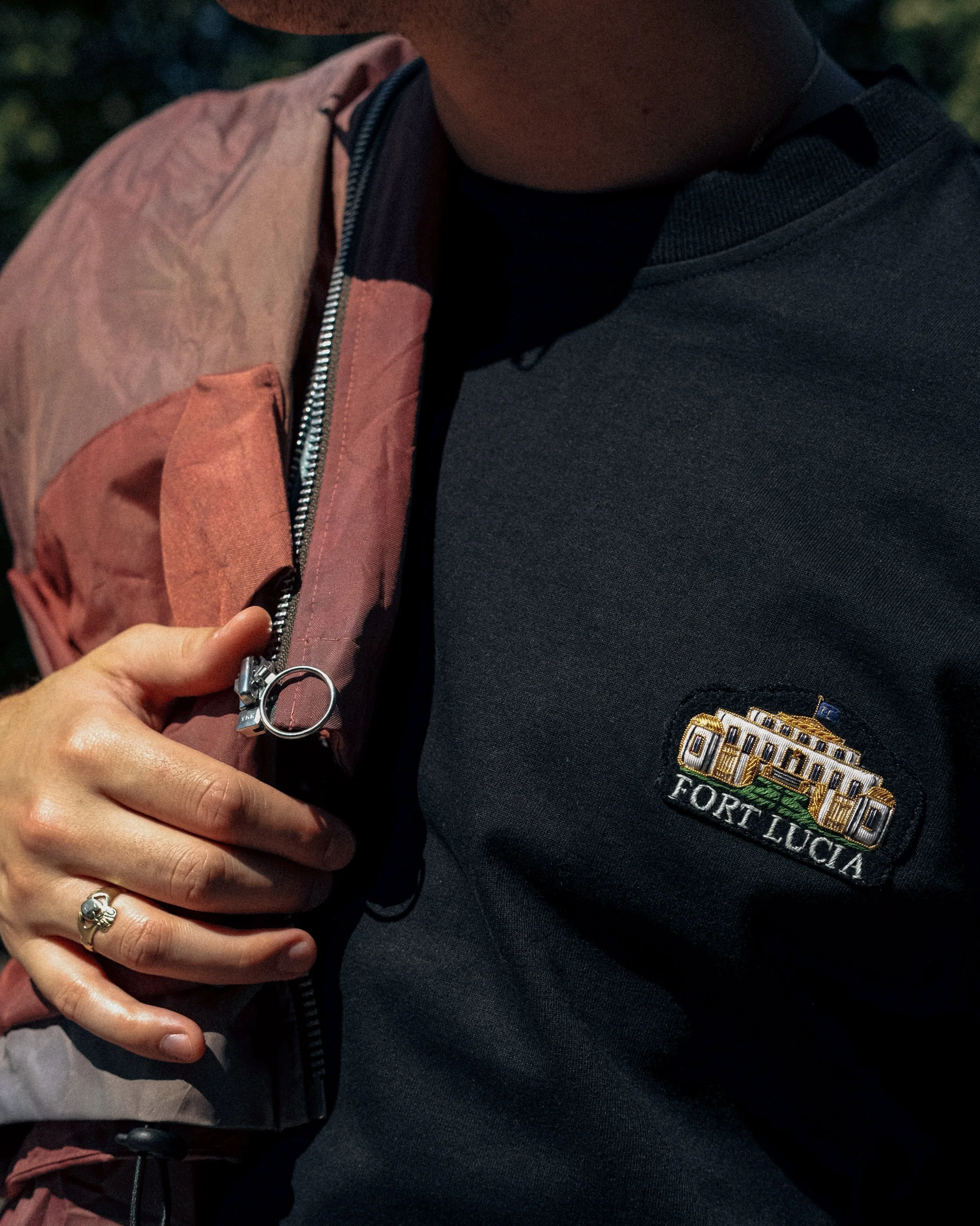 Close-up of a person's shoulder and chest, showing a Civil Air Patrol patch on a dark navy shirt and holding a backpack strap with a hand that has a silver ring with a clover design.